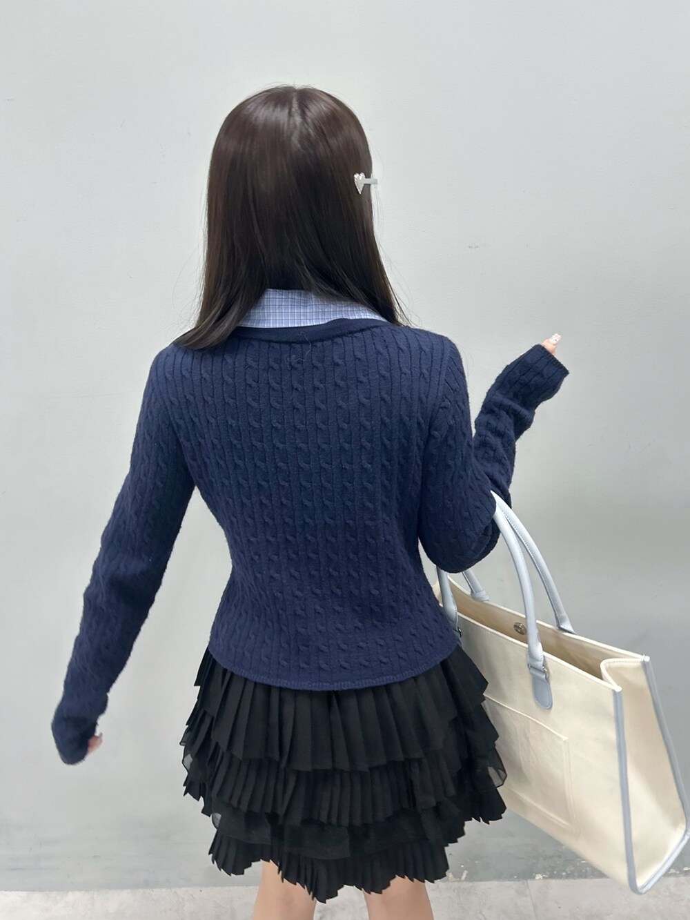 ブルー系のニット/セーター、ブラック系のスカート、ブルー系のトートバッグを着用したレディースの冬コーディネートの9枚目の写真