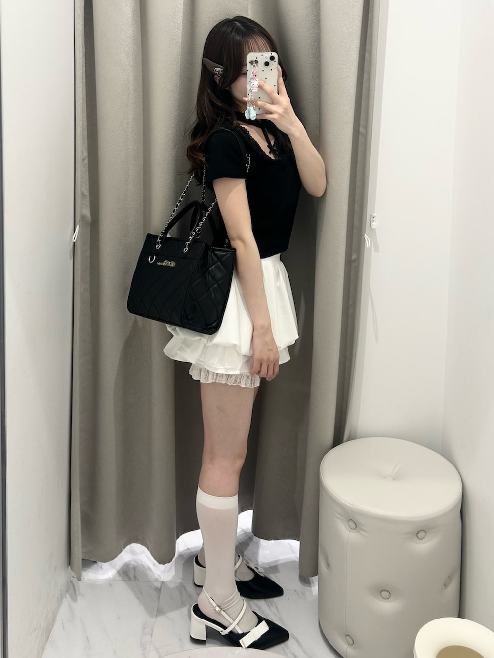 ブラック系のトートバッグ、ホワイト系のスカート、ブラック系のTシャツ/カットソーを着用したレディースの春コーディネートの6枚目の写真