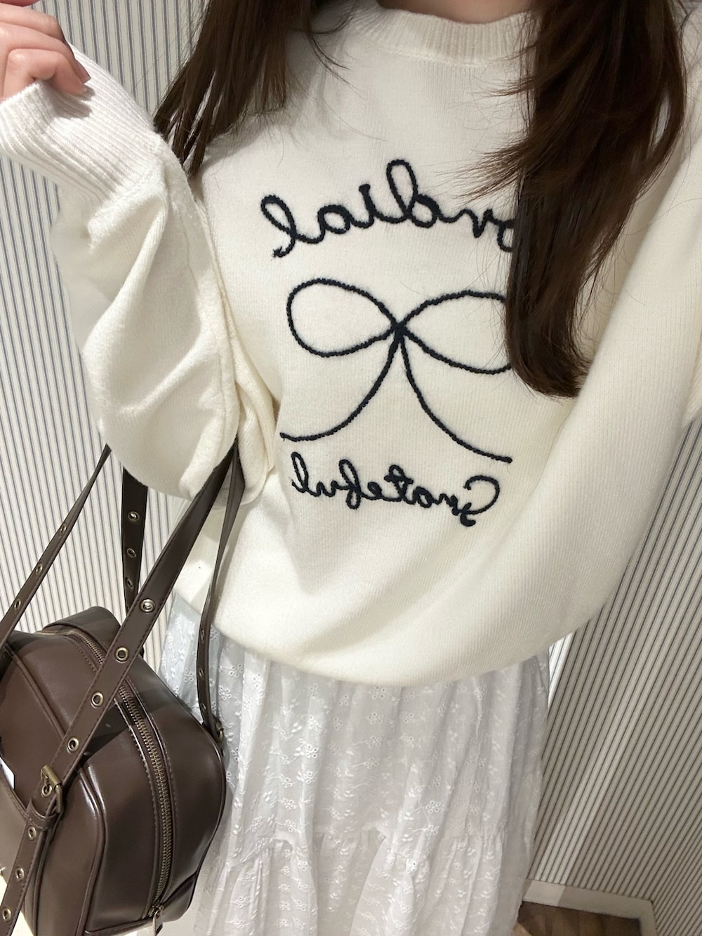 ピンク系のニット/セーター、ホワイト系のスカート、ホワイト系のショルダーバッグを着用したレディースの冬コーディネートの4枚目の写真