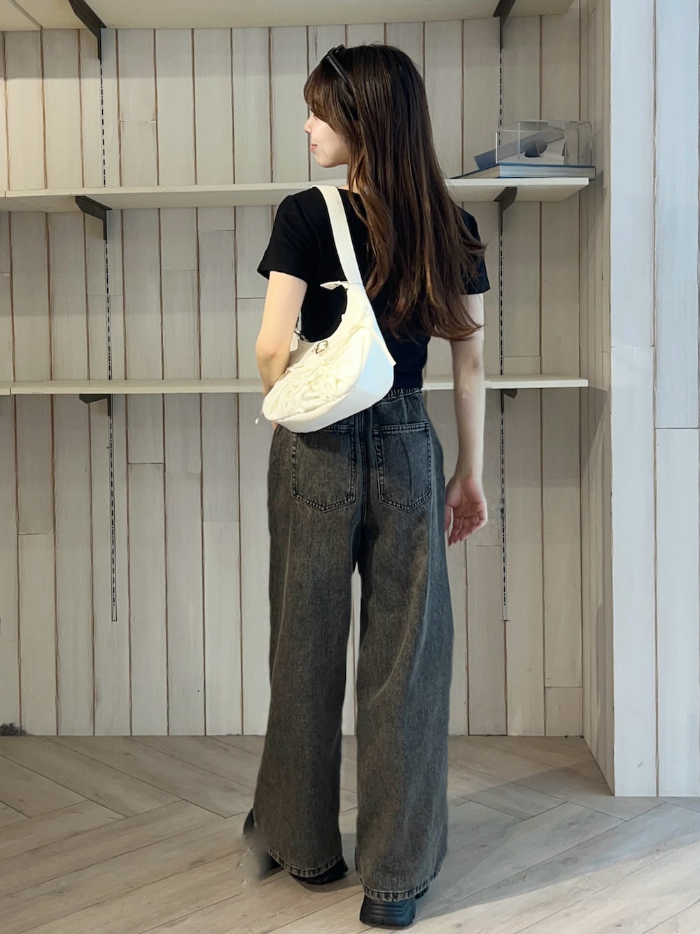 ブラック系のTシャツ/カットソー、ブラック系のデニムパンツ、ホワイト系のショルダーバッグを着用したレディースの春コーディネートの5枚目の写真