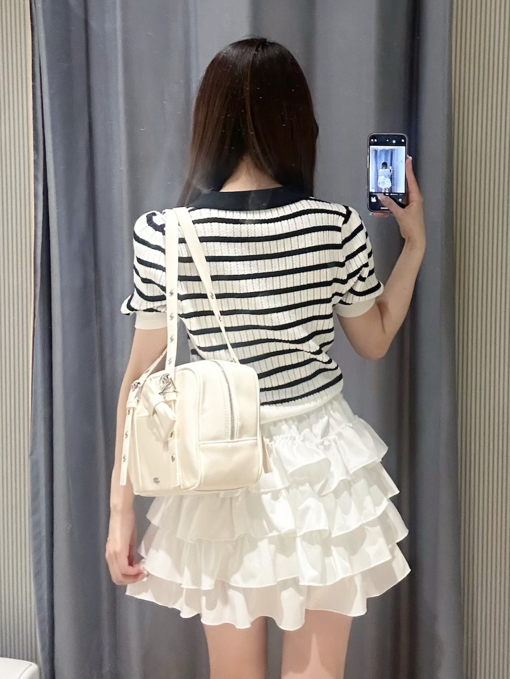 その他のポロシャツ、ホワイト系のスカート、ホワイト系のショルダーバッグを着用したレディースの夏コーディネートの5枚目の写真