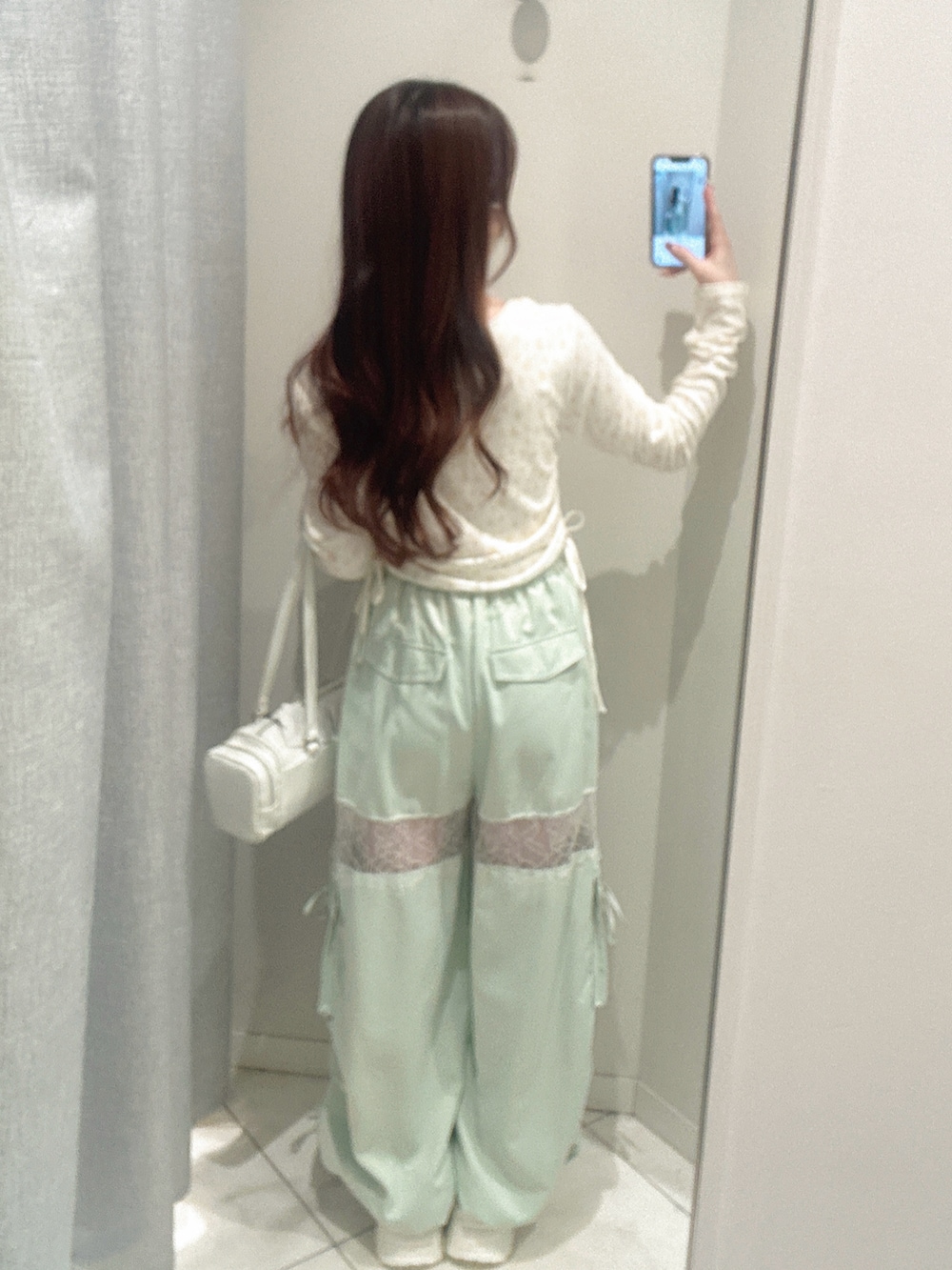 ホワイト系のスニーカー、グリーン系のカーゴパンツ、ホワイト系のトートバッグを着用したレディースの冬コーディネートの3枚目の写真