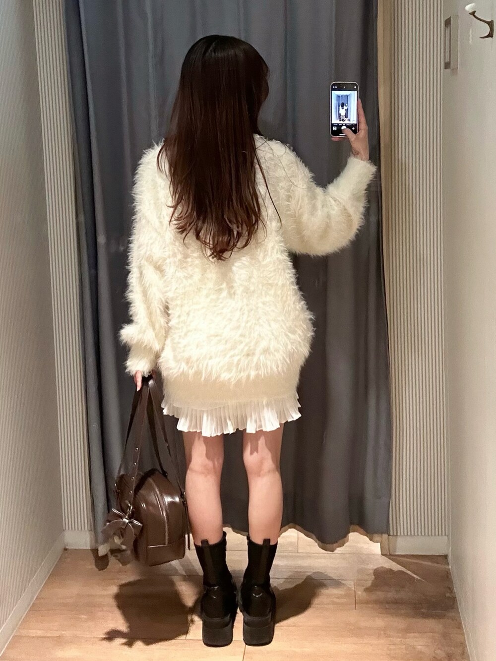 ブラウン系のショルダーバッグ、ホワイト系のカーディガン/ボレロ、ホワイト系のワンピースを着用したレディースの冬コーディネートの5枚目の写真