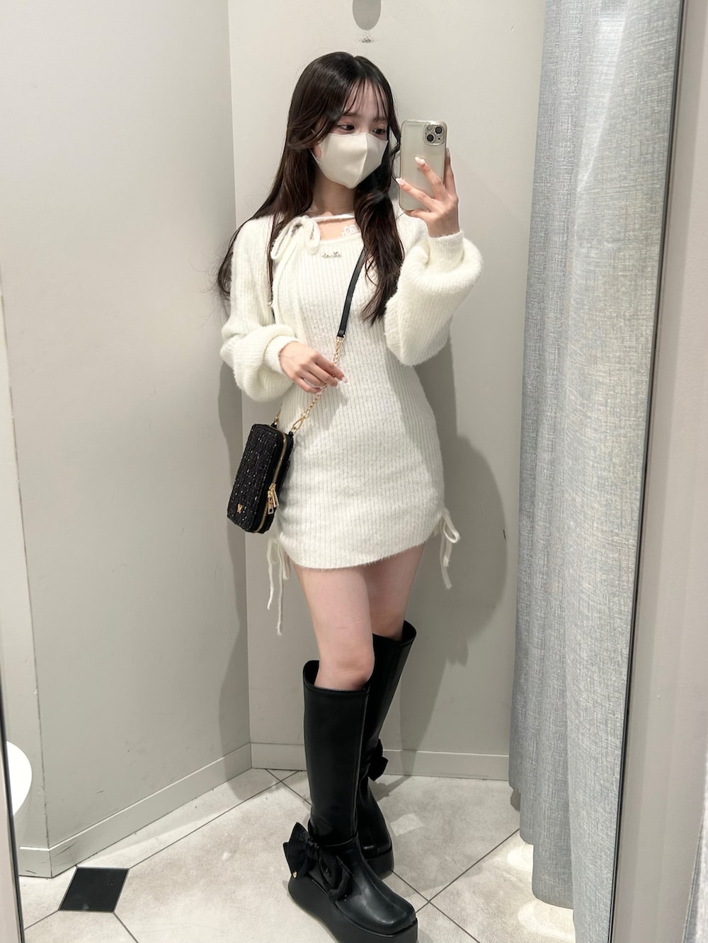 ブラック系のショルダーバッグ、ブラック系のブーツ、ホワイト系のワンピースを着用したレディースの秋コーディネートの4枚目の写真