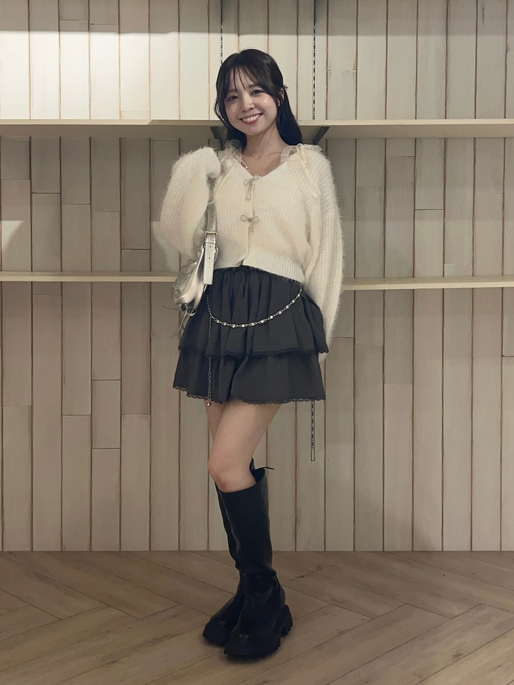 ホワイト系のカーディガン/ボレロ、シルバー系のショルダーバッグ、グレー系のスカートを着用したレディースの秋コーディネートの3枚目の写真