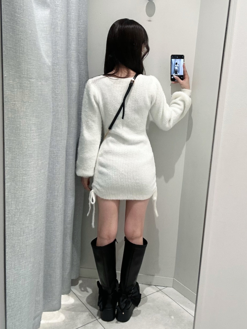 ブラック系のショルダーバッグ、ブラック系のブーツ、ホワイト系のワンピースを着用したレディースの秋コーディネートの5枚目の写真