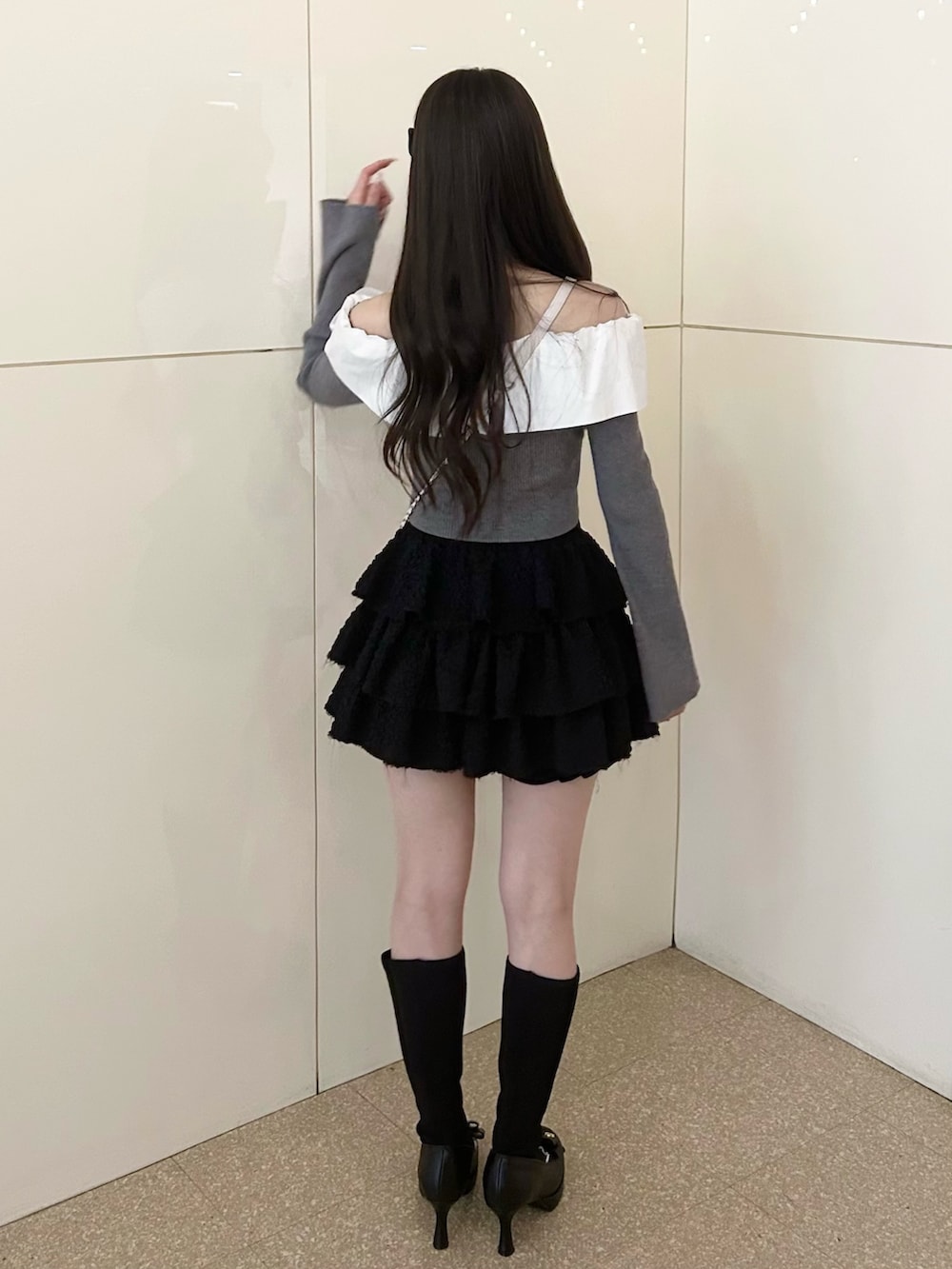 グレー系のニット/セーター、ホワイト系のショルダーバッグ、ブラック系のスカートを着用したレディースの冬コーディネートの3枚目の写真