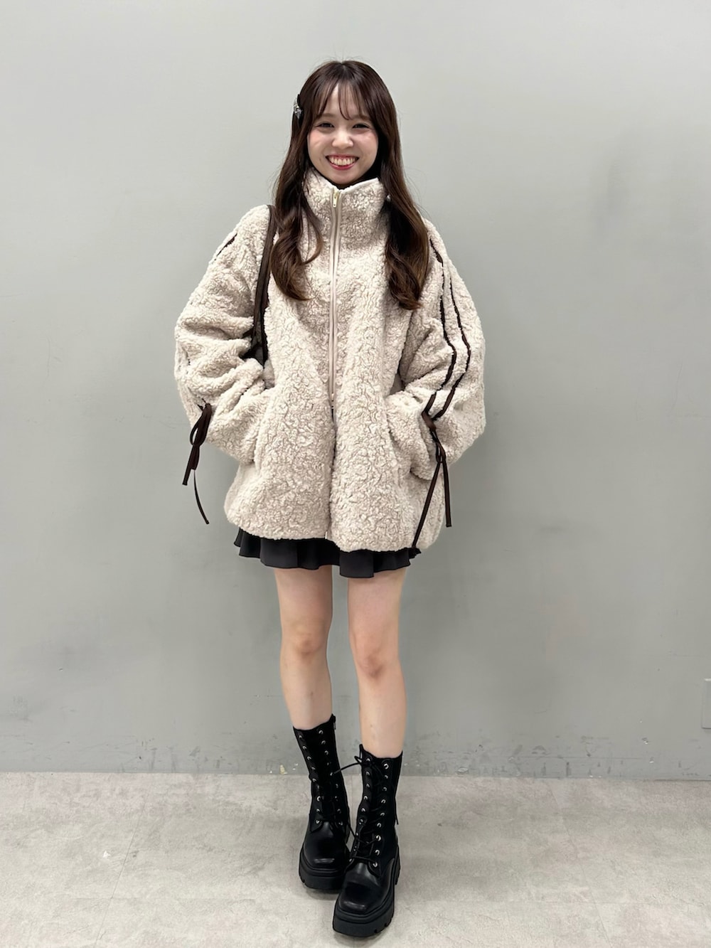 ベージュ系のブルゾン、ブラック系のショルダーバッグ、グレー系のスカートを着用したレディースの冬コーディネートの2枚目の写真