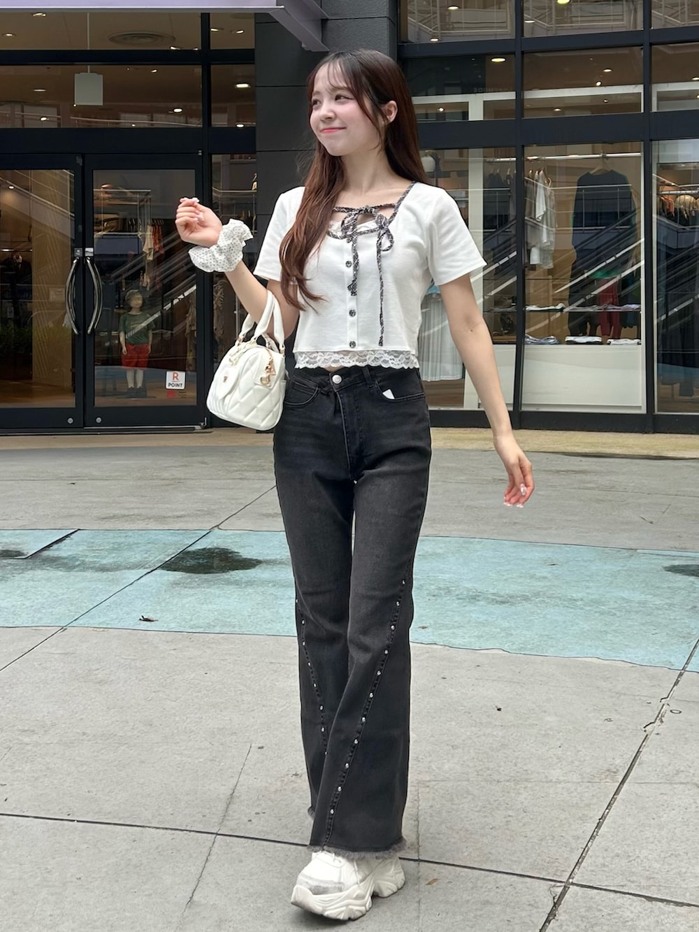 ブラック系のデニムパンツ、ホワイト系のボストンバッグ、ホワイト系のスニーカーを着用したレディースの夏コーディネートの2枚目の写真