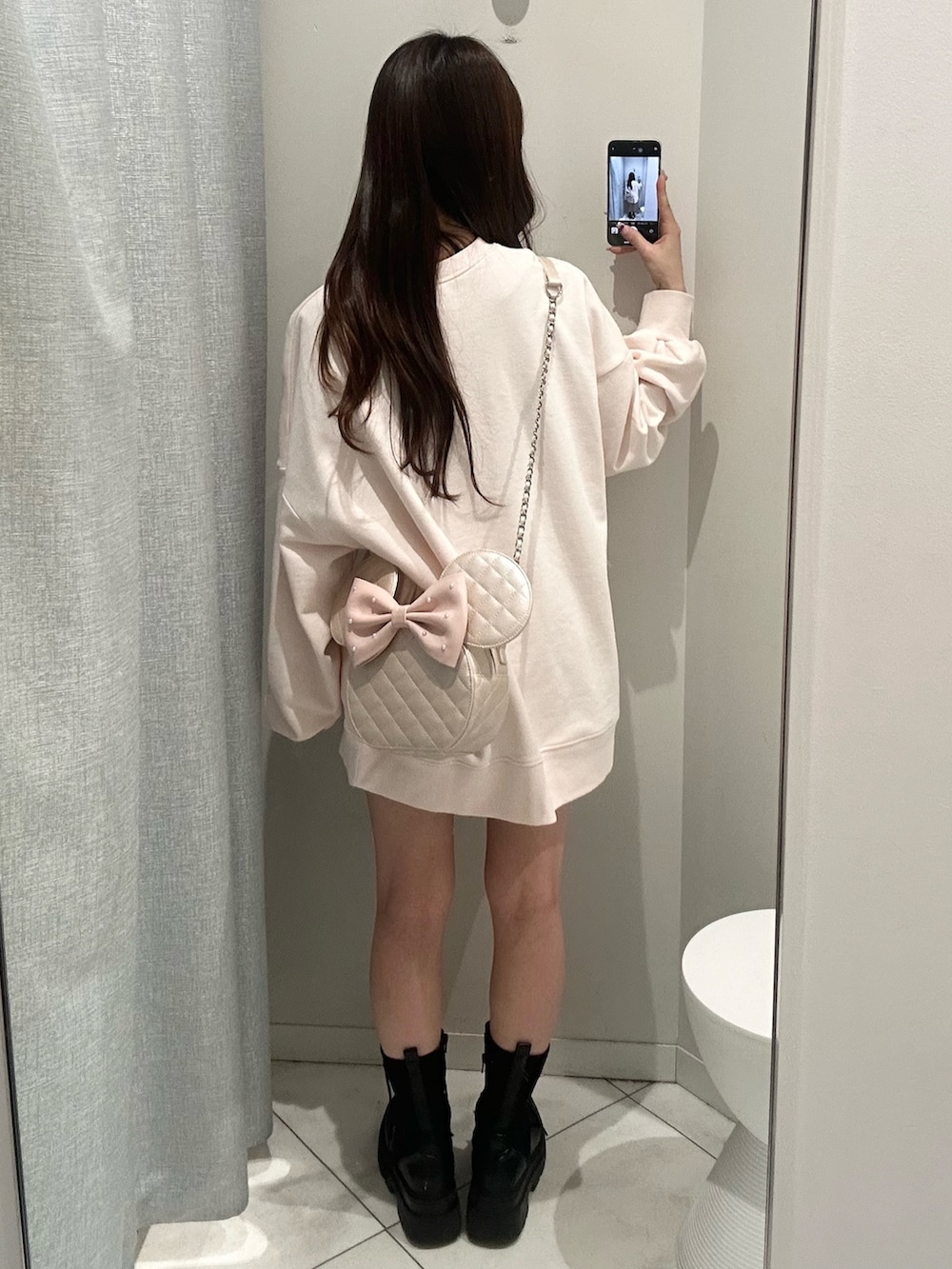 ピンク系のスウェット、ピンク系のショルダーバッグを着用したレディースの冬コーディネートの5枚目の写真