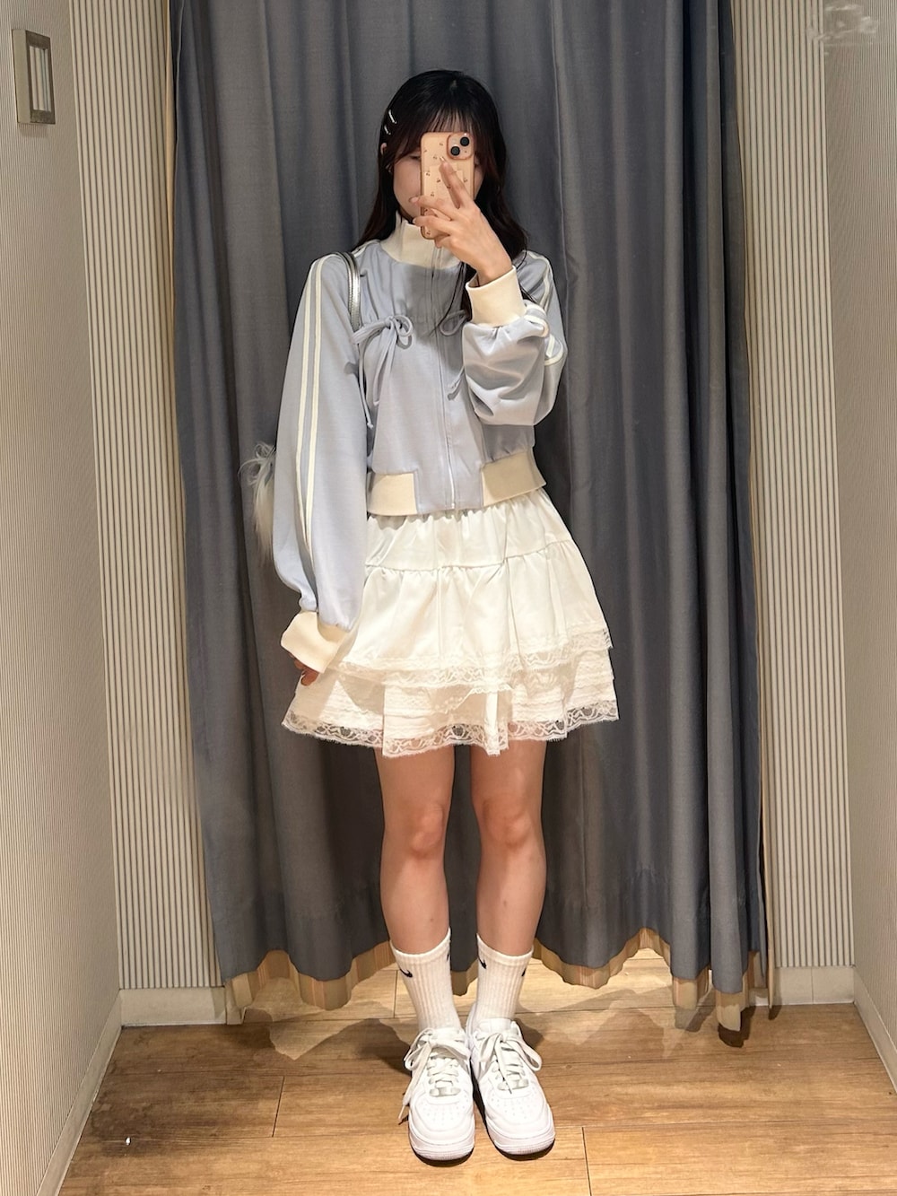 ホワイト系のスカート、ブラック系のスウェット、ホワイト系のスニーカーを着用したレディースの秋コーディネートの3枚目の写真