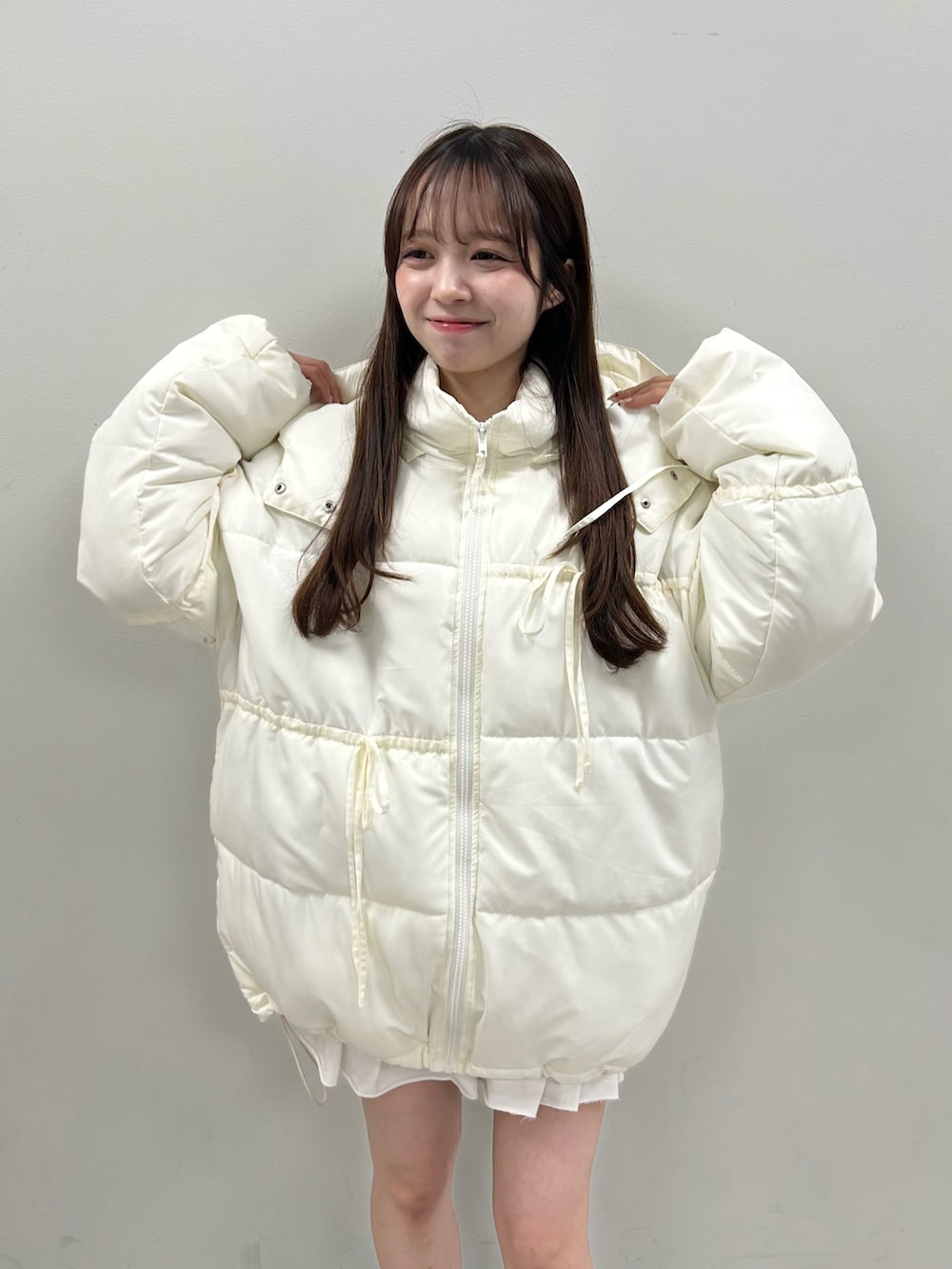 ホワイト系のダウンジャケット/コート、ホワイト系のスカート、ブラウン系のTシャツ/カットソーを着用したレディースの冬コーディネートの2枚目の写真