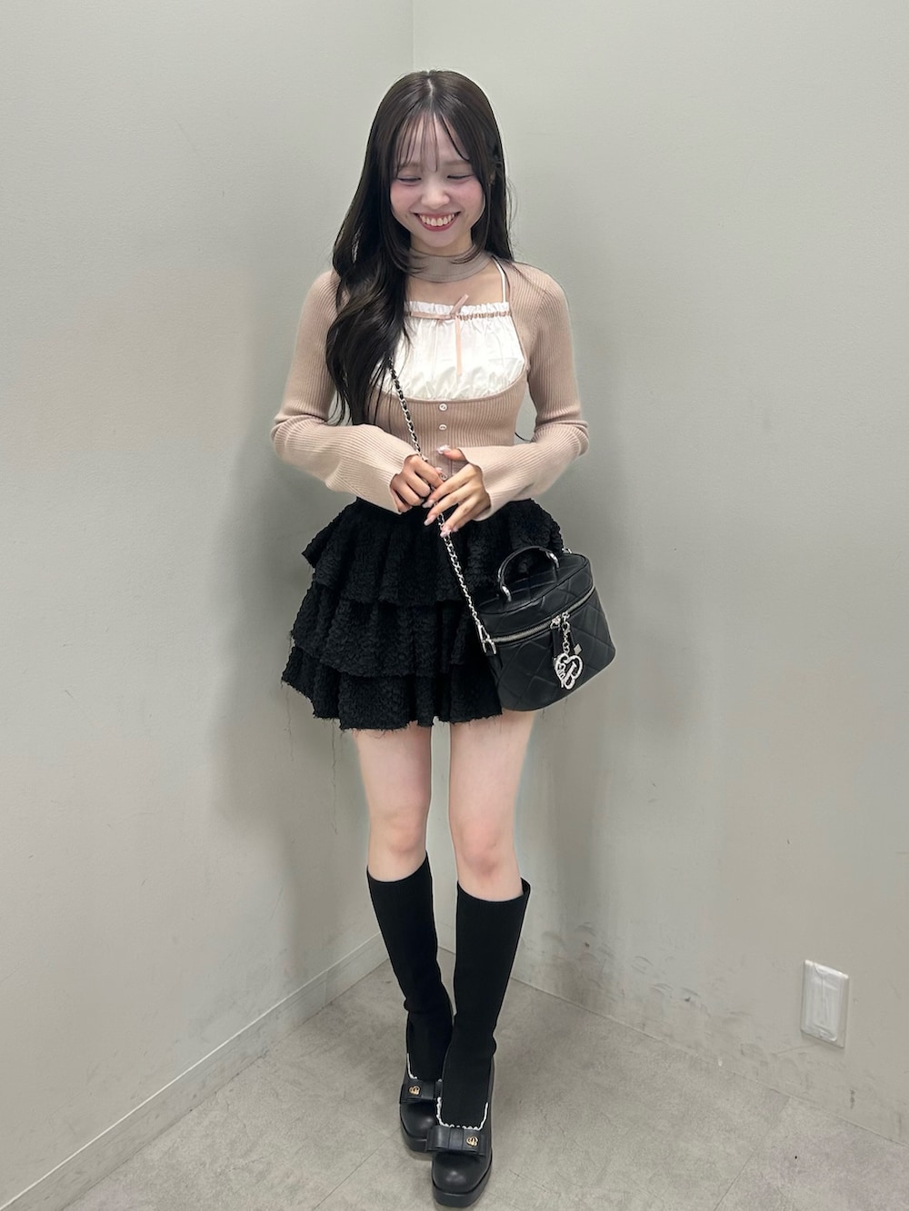 ベージュ系のニット/セーター、ブラック系のスカート、ブラック系のショルダーバッグを着用したレディースの春コーディネートの6枚目の写真