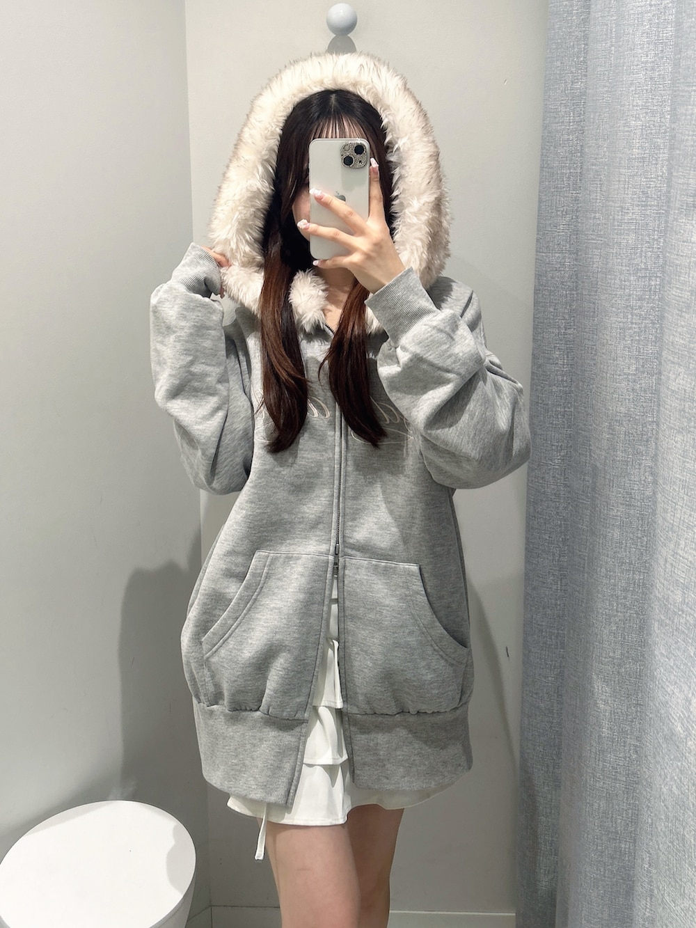 グレー系のパーカー、ホワイト系のスカートを着用したレディースの秋コーディネートの2枚目の写真