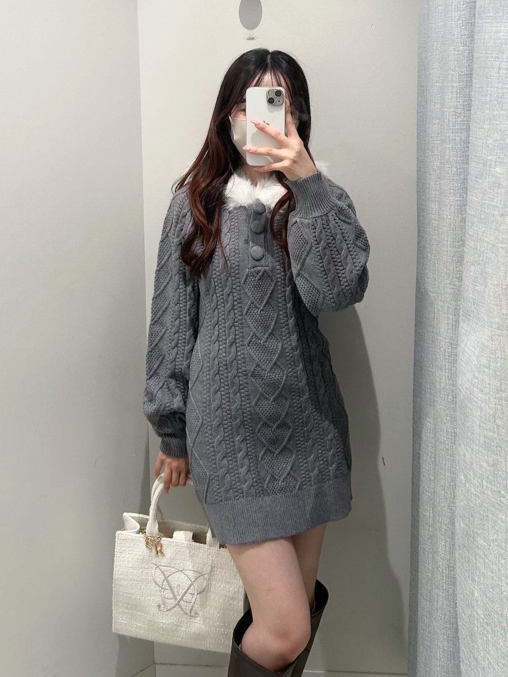 グレー系のワンピース、ホワイト系のトートバッグ、ブラウン系のブーツを着用したレディースの秋コーディネートの2枚目の写真