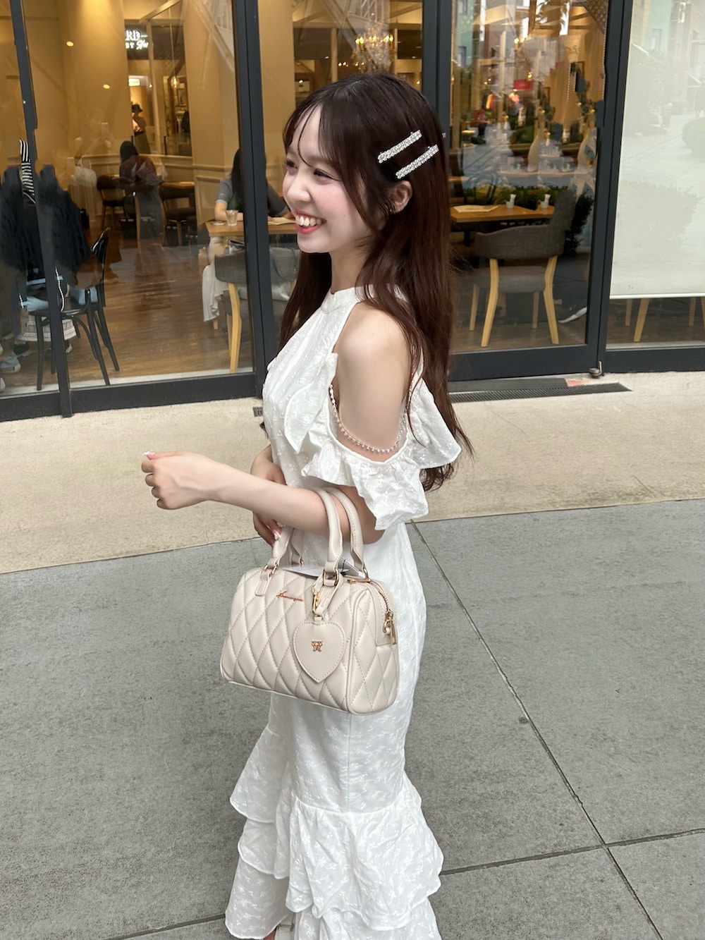 ホワイト系のワンピース、ベージュ系のボストンバッグ、ホワイト系のサンダルを着用したレディースの夏コーディネートの5枚目の写真