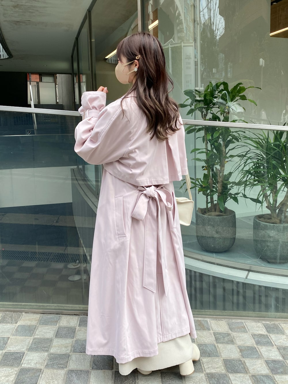 ピンク系のトレンチコート、ホワイト系のワンピース、ホワイト系のショルダーバッグを着用したレディースの春コーディネートの3枚目の写真