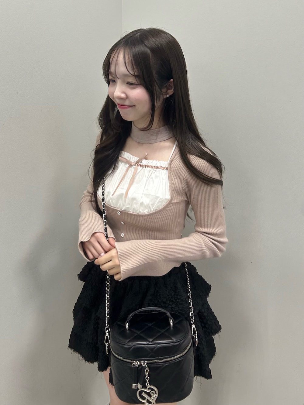 ベージュ系のニット/セーター、ブラック系のスカート、ブラック系のショルダーバッグを着用したレディースの春コーディネートの2枚目の写真