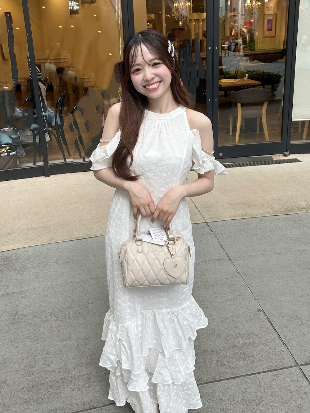 ホワイト系のワンピース、ベージュ系のボストンバッグ、ホワイト系のサンダルを着用したレディースの夏コーディネートの3枚目の写真