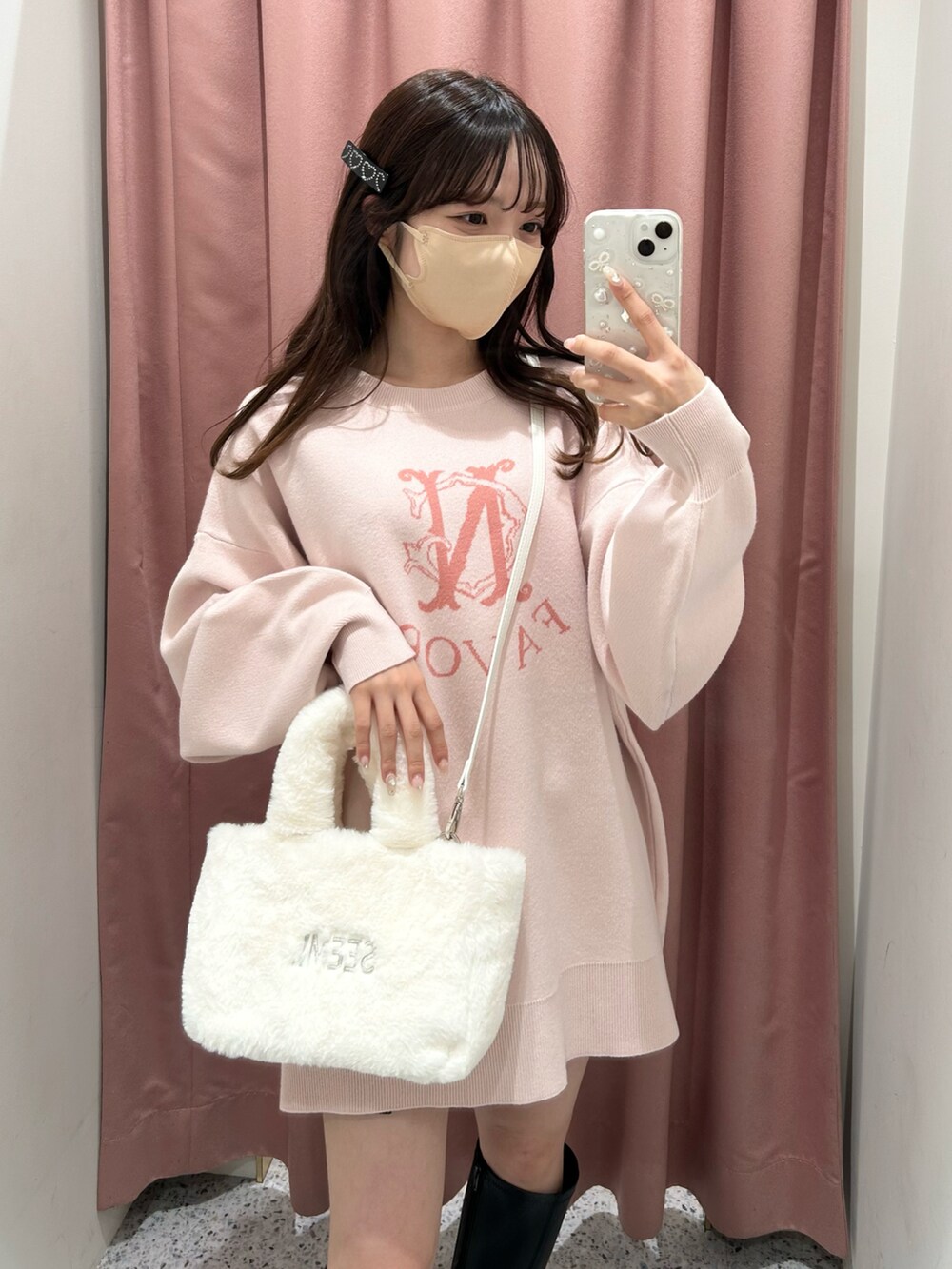 ピンク系のニット/セーター、ホワイト系のトートバッグ、ブラック系のブーツを着用したレディースの冬コーディネートの5枚目の写真