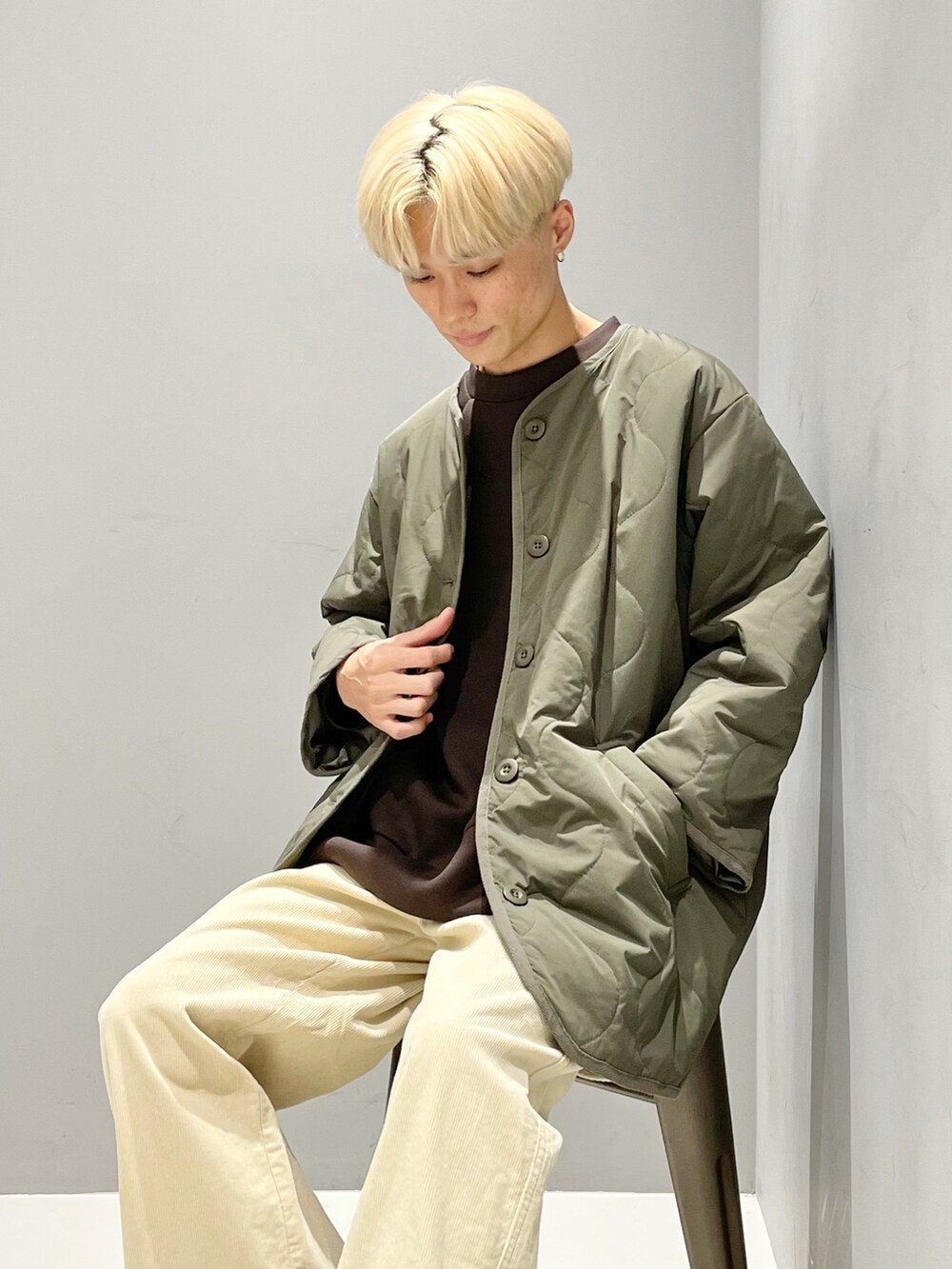 グリーン系のノーカラージャケット、ブラウン系のスウェット、ホワイト系のカーゴパンツを着用したメンズの秋コーディネートの2枚目の写真