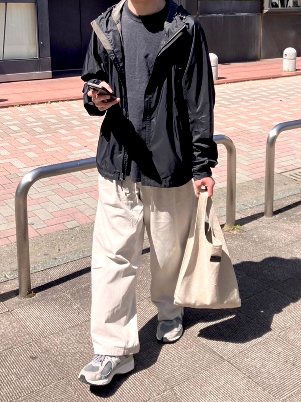 ブラック系のTシャツ/カットソー、ホワイト系のチノパンツ、グレー系のバッグを着用したメンズの春コーディネートの2枚目の写真