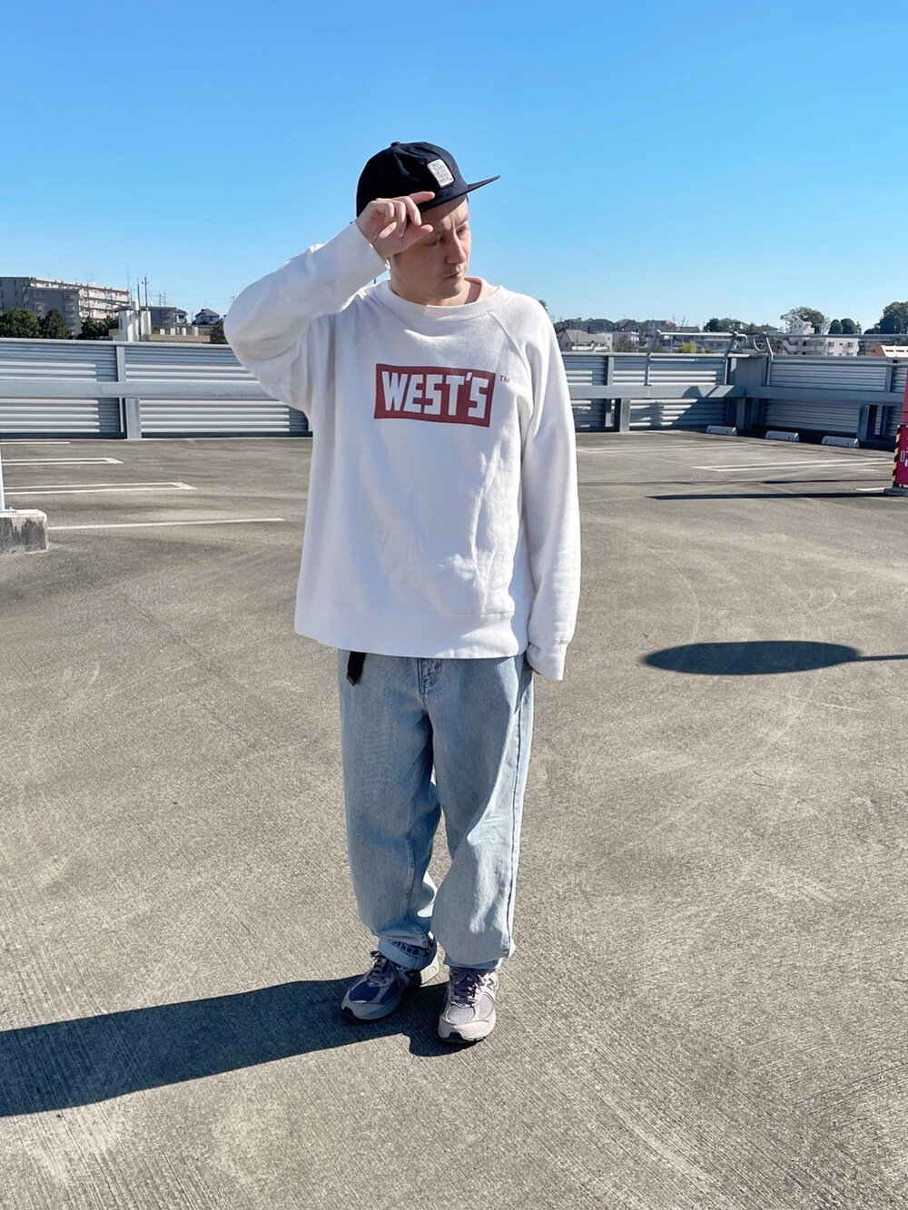 ホワイト系のスウェット、ブルー系のデニムパンツ、グレー系のスニーカーを着用したメンズの秋コーディネートの2枚目の写真