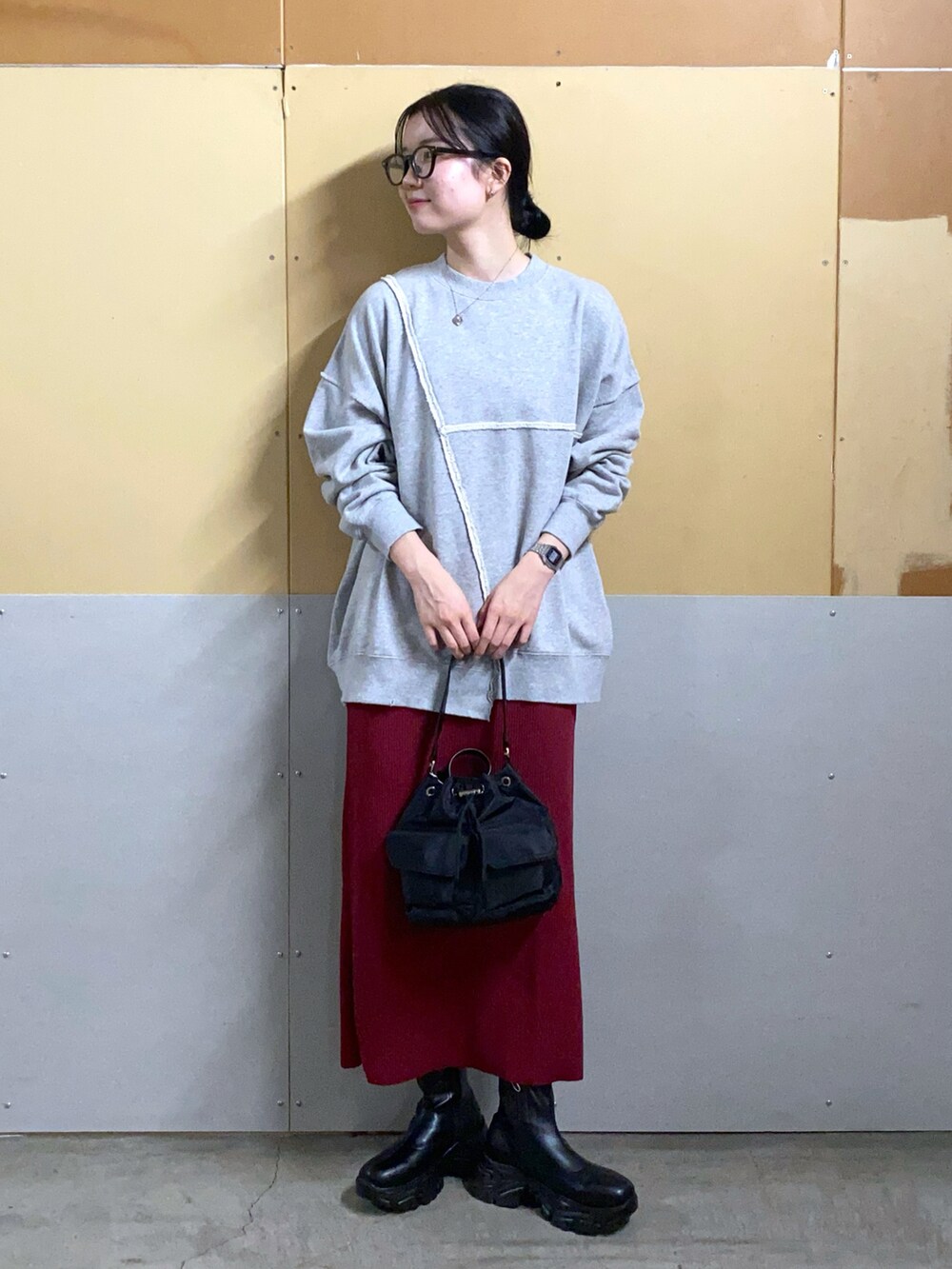 グレー系のスウェット、レッド系のスカート、ブラック系のショルダーバッグを着用したレディースの秋コーディネートの2枚目の写真