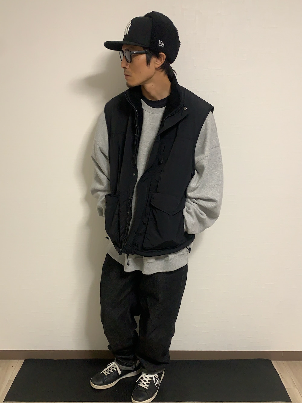 グレー系のスウェット、ブラック系のベスト、ブラック系のスニーカーを着用したメンズの秋コーディネートの2枚目の写真