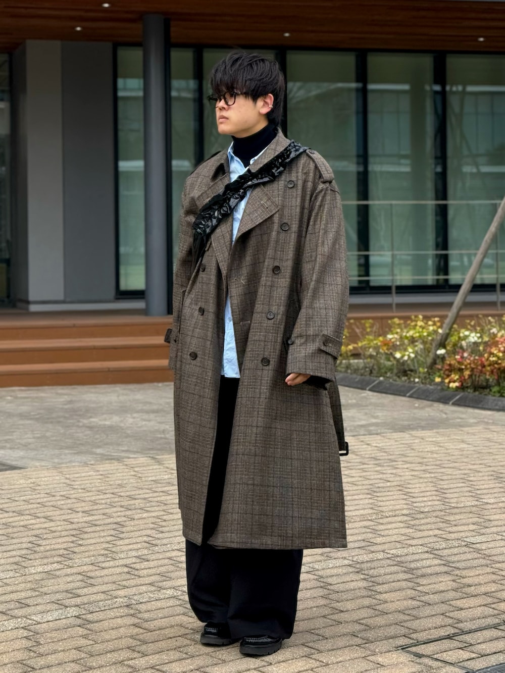 グレー系のトレンチコート、ブラック系のスラックス、ブラック系のローファーを着用したメンズの春コーディネートの2枚目の写真