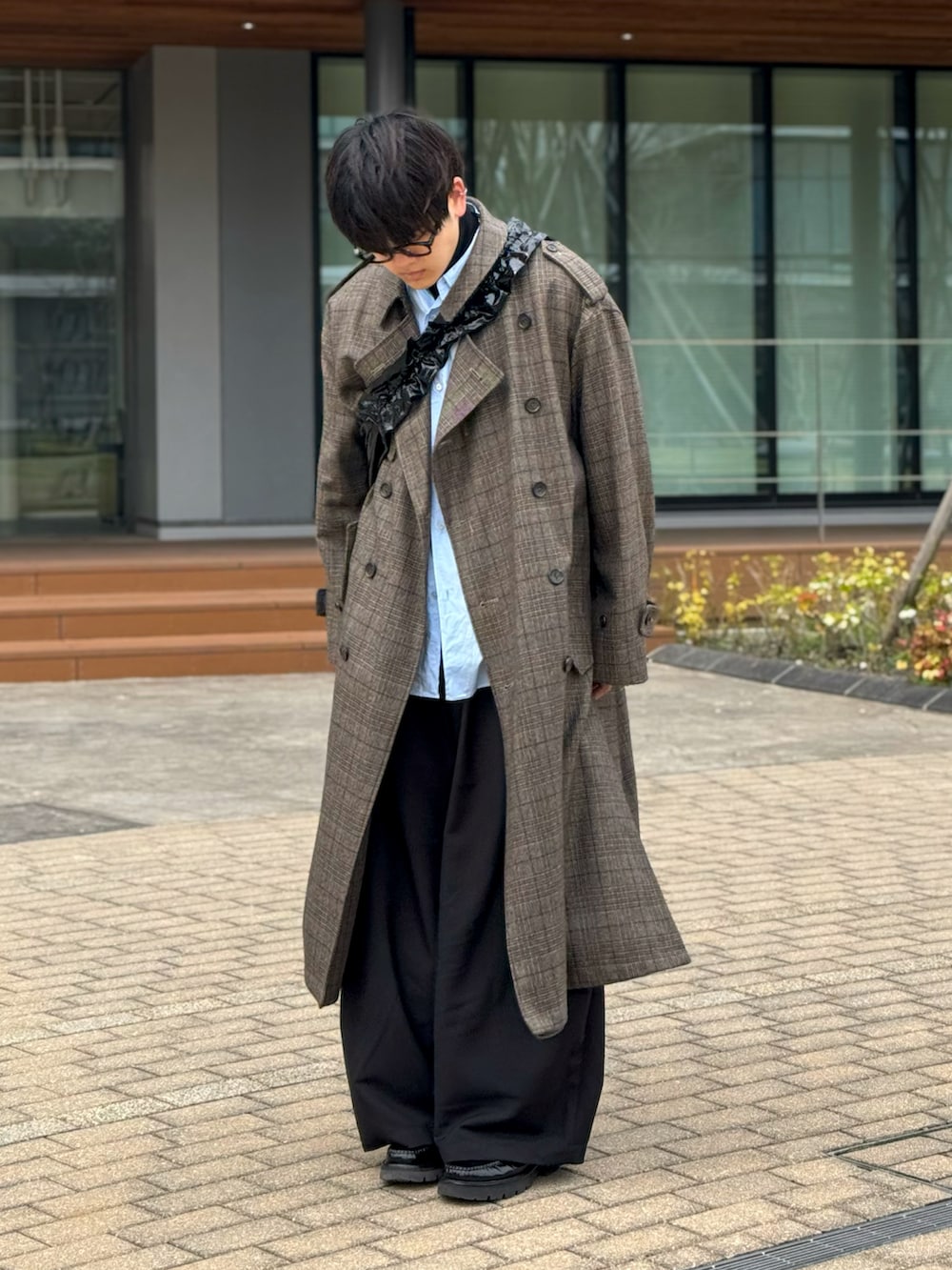 グレー系のトレンチコート、ブラック系のスラックス、ブラック系のローファーを着用したメンズの春コーディネートの3枚目の写真