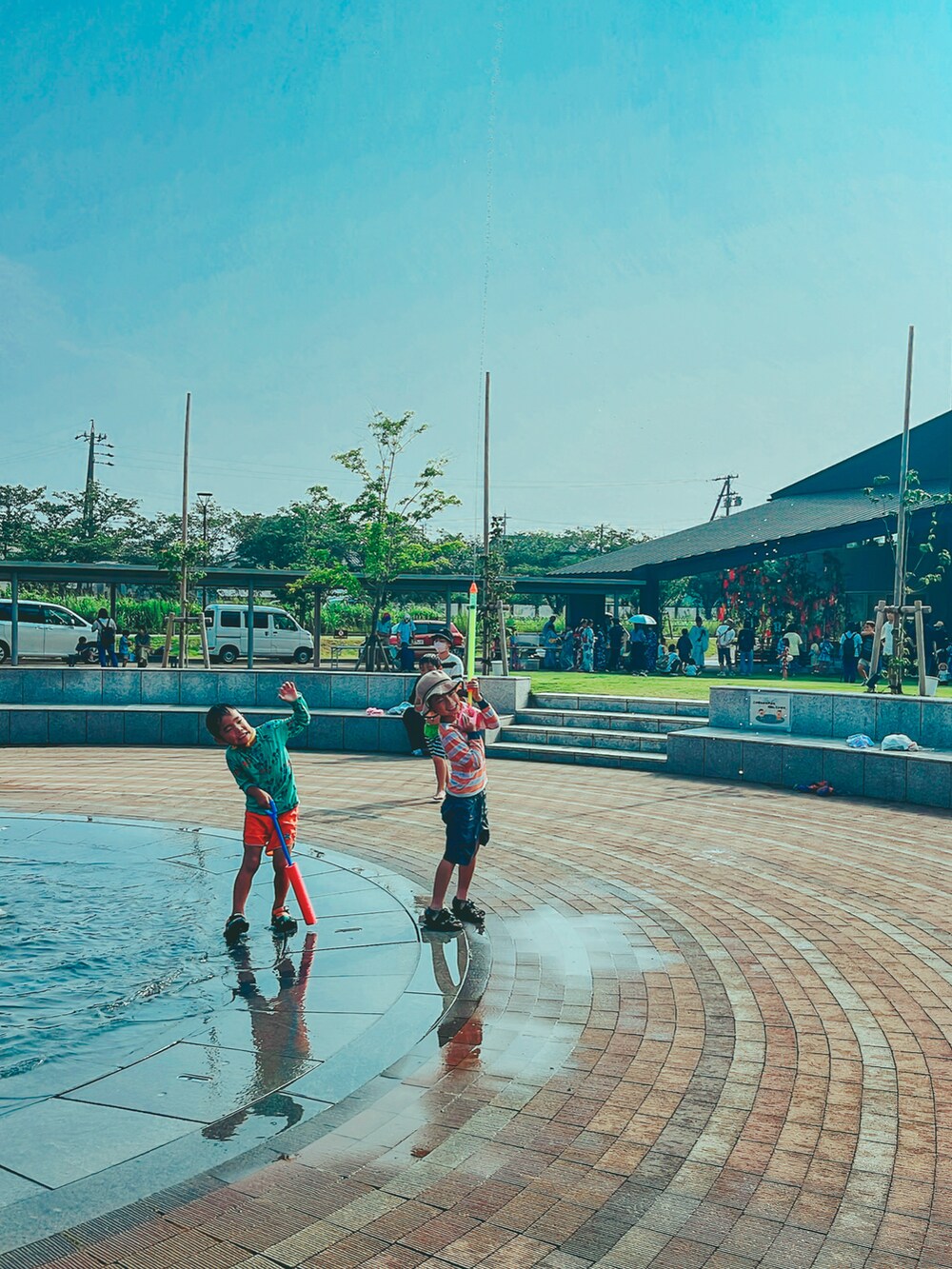 ブラック系のサンダル、グレー系のパンツ、オレンジ系のラッシュガードを着用したキッズの夏コーディネートの2枚目の写真