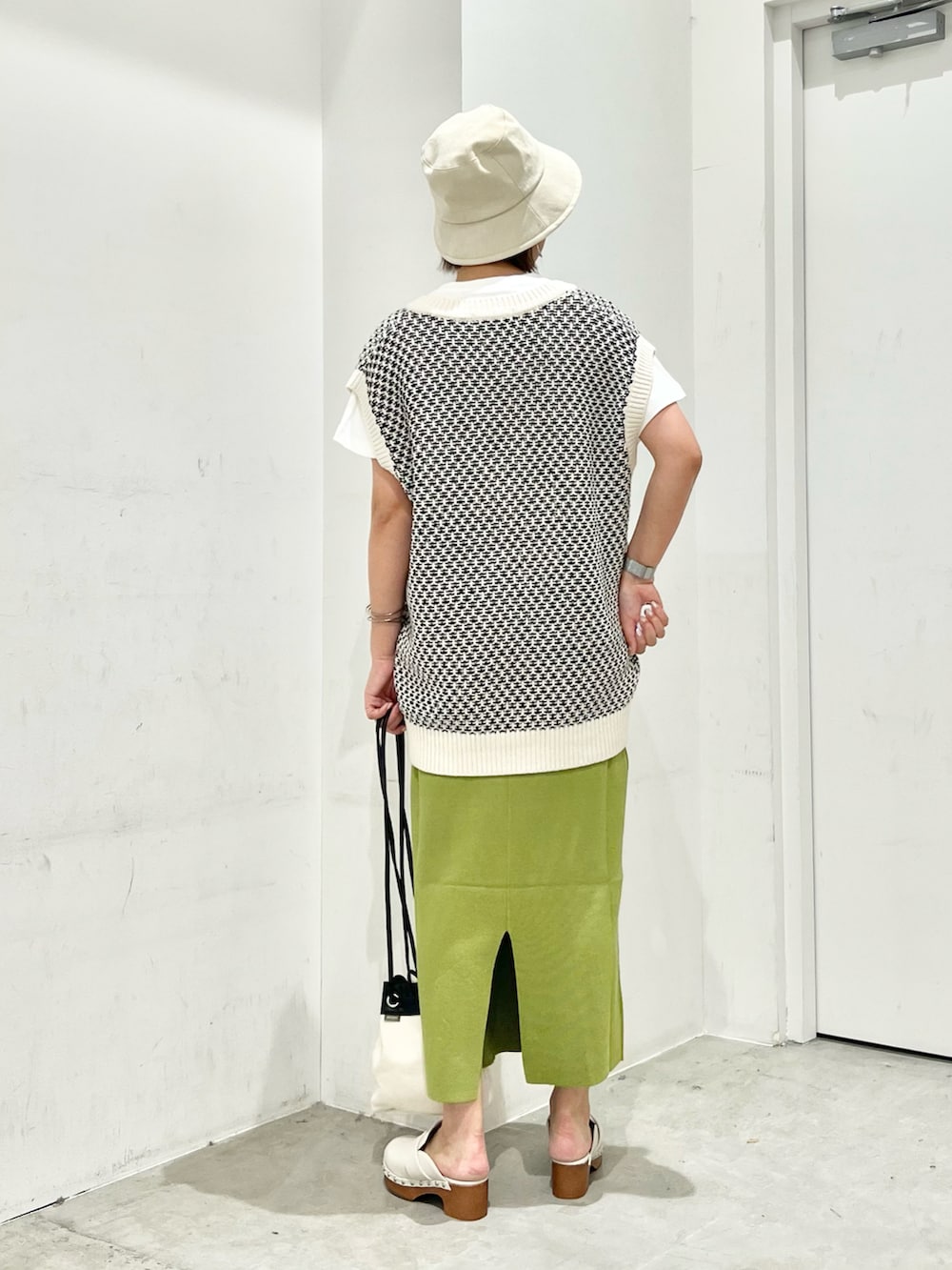 ホワイト系のベスト、ホワイト系のTシャツ/カットソー、ブラック系のショルダーバッグを着用したレディースの夏コーディネートの4枚目の写真