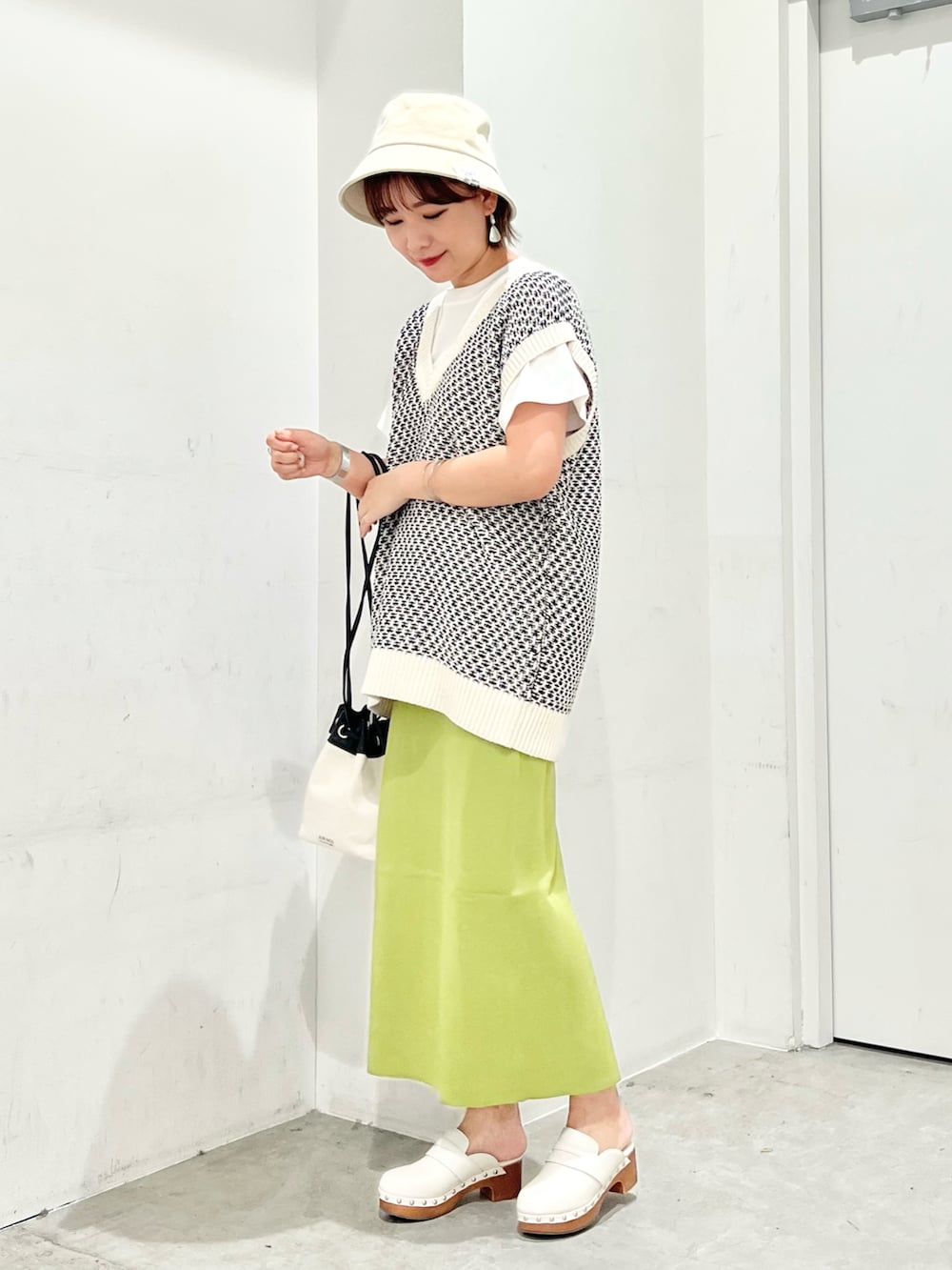 ホワイト系のベスト、ホワイト系のTシャツ/カットソー、ブラック系のショルダーバッグを着用したレディースの夏コーディネートの2枚目の写真