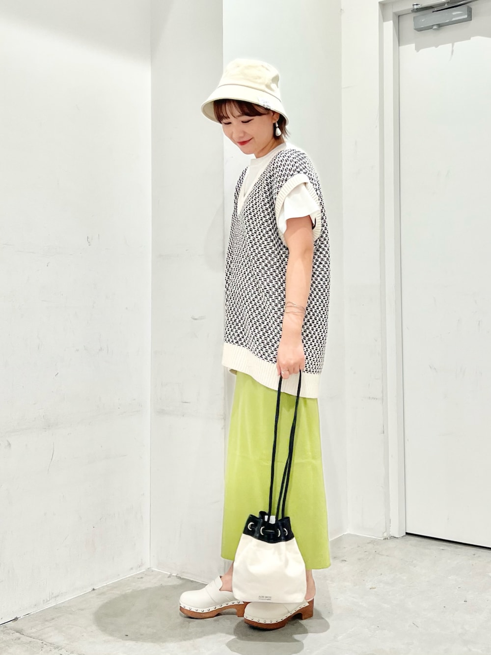 ホワイト系のベスト、ホワイト系のTシャツ/カットソー、ブラック系のショルダーバッグを着用したレディースの夏コーディネートの3枚目の写真