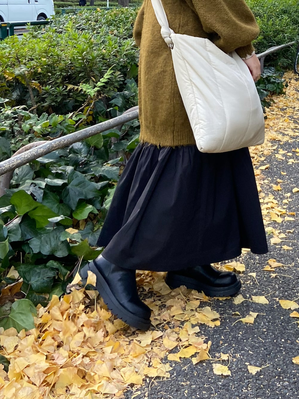 グリーン系のニット/セーター、ブラック系のスカート、ブラック系のブーツを着用したレディースの冬コーディネートの2枚目の写真