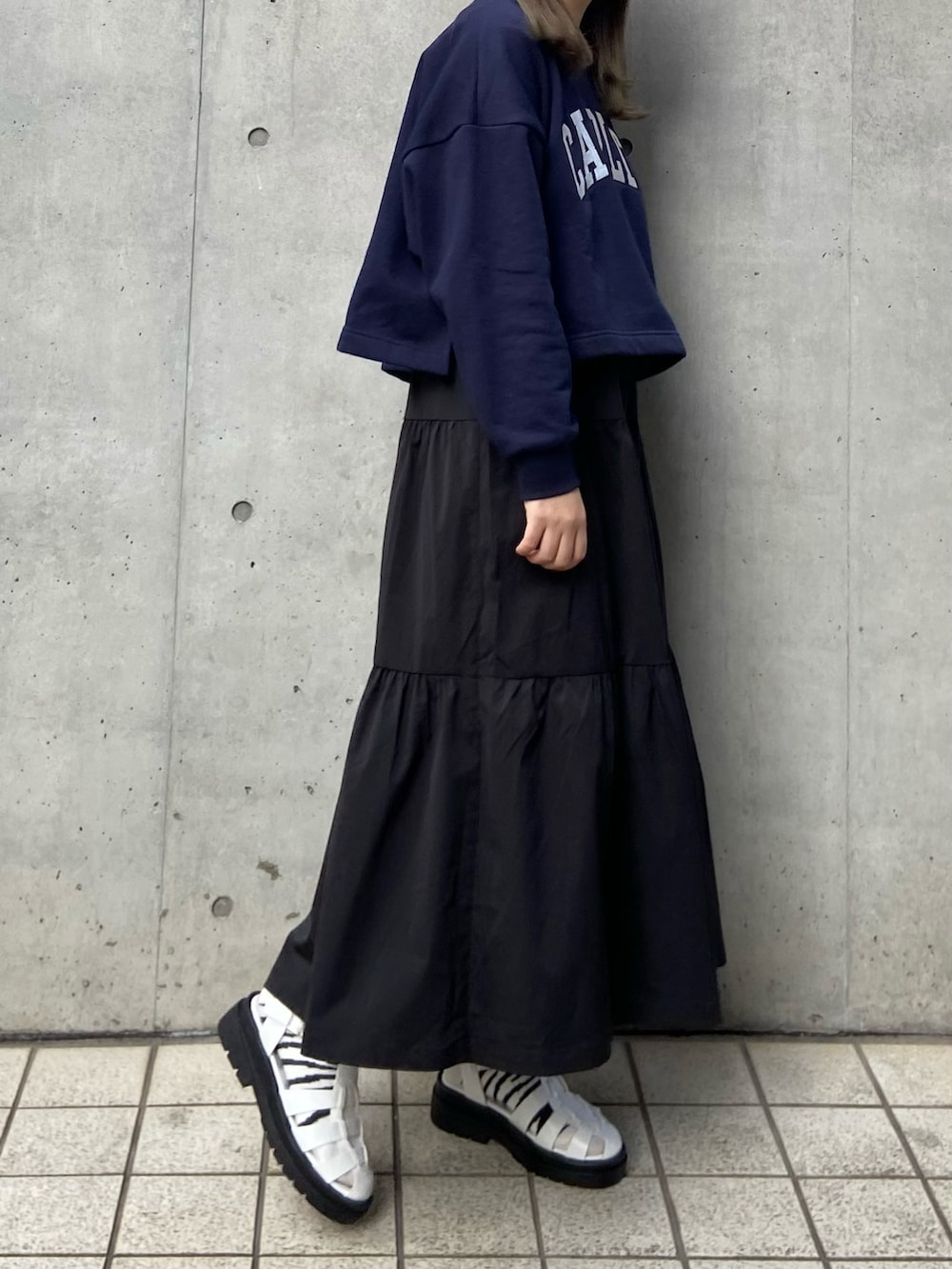 ホワイト系のサンダル、グレー系のスウェット、ブラック系のスカートを着用したレディースの冬コーディネートの3枚目の写真