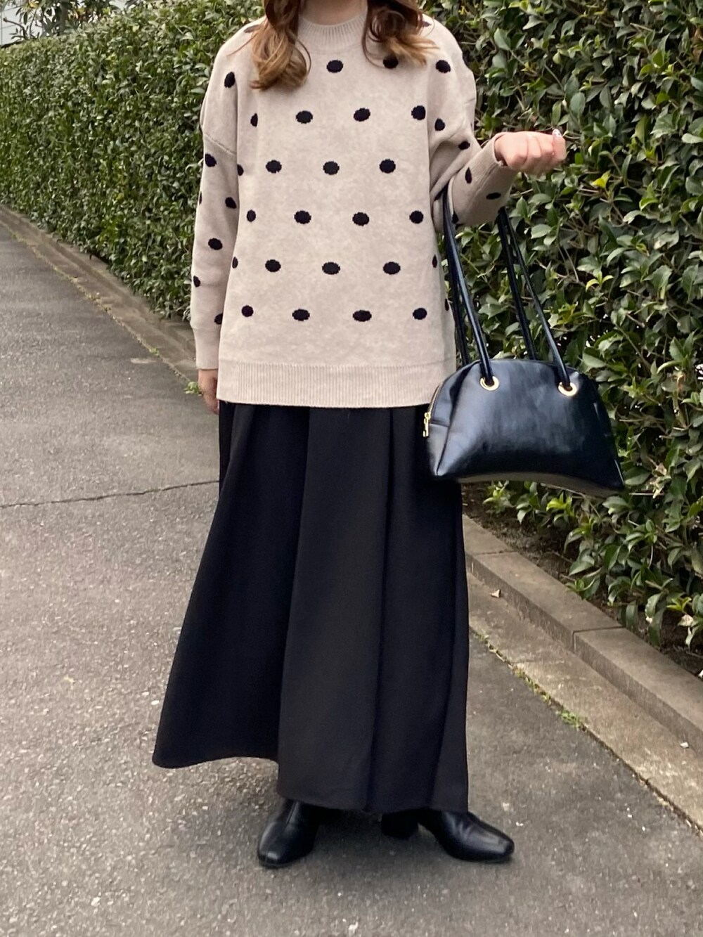 ベージュ系のニット/セーター、ブラック系のハンドバッグ、ブラック系のブーツを着用したレディースの春コーディネートの2枚目の写真