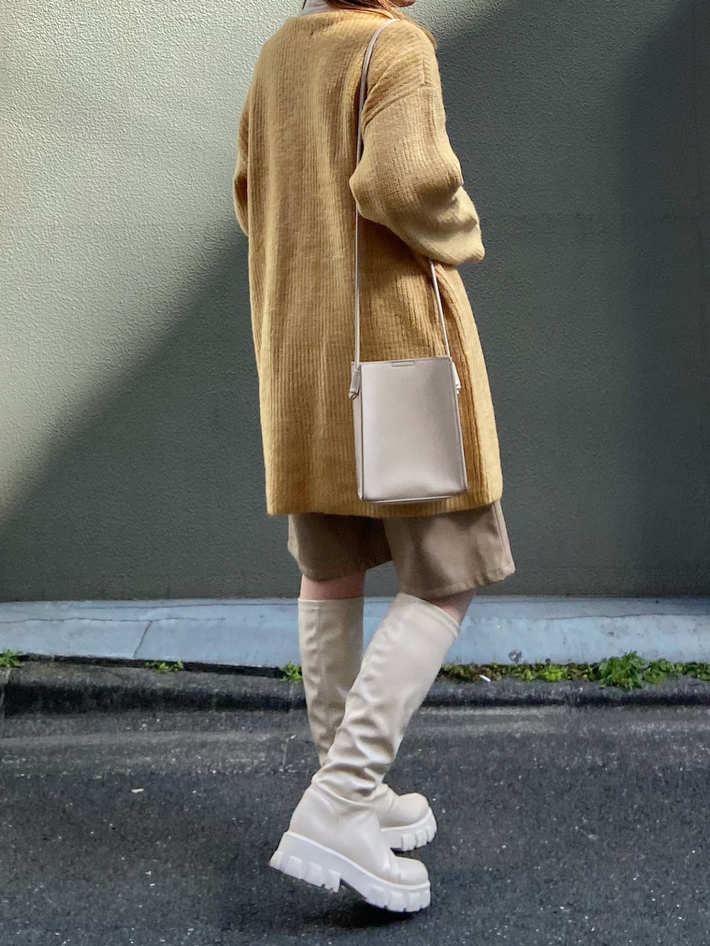 イエロー系のニット/セーター、ベージュ系のその他パンツ、ベージュ系のブーツを着用したレディースの冬コーディネートの3枚目の写真