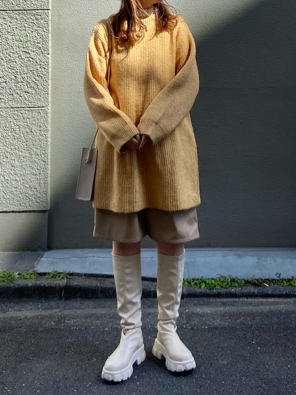 イエロー系のニット/セーター、ベージュ系のその他パンツ、ベージュ系のブーツを着用したレディースの冬コーディネートの2枚目の写真