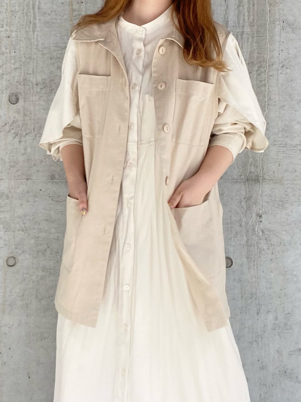 ベージュ系のベスト、ホワイト系のワンピース、ベージュ系のスニーカーを着用したレディースの夏コーディネートの3枚目の写真