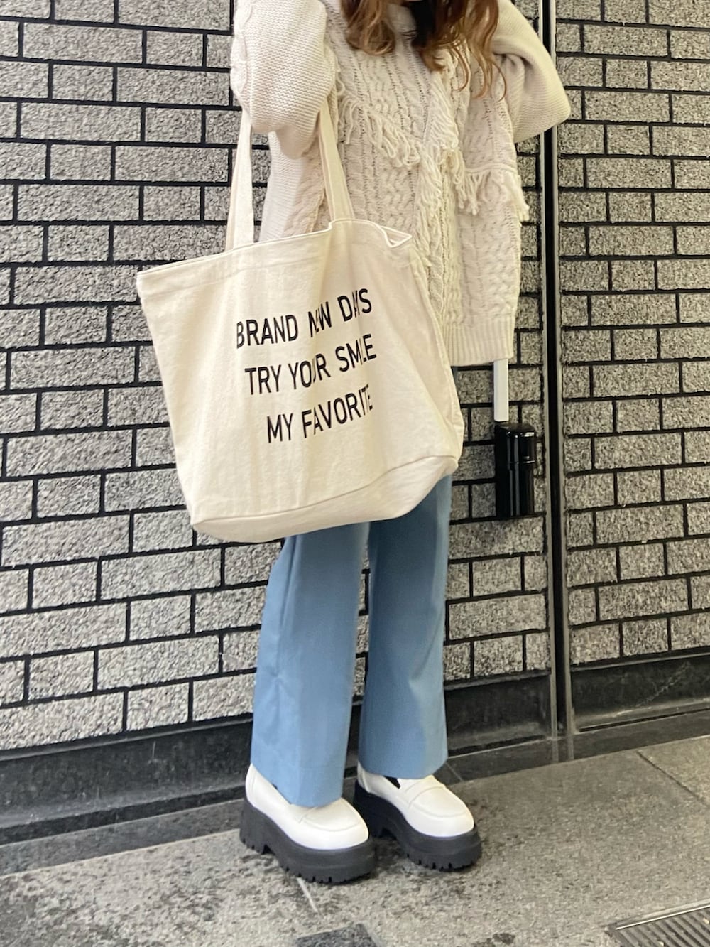 ホワイト系のニット/セーター、ホワイト系のトートバッグ、ホワイト系のローファーを着用したレディースの冬コーディネートの2枚目の写真