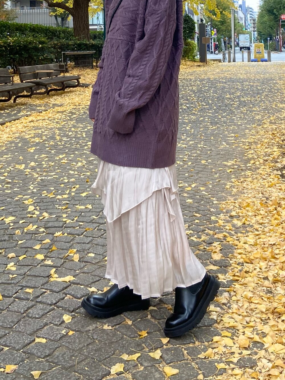 パープル系のニット/セーター、ホワイト系のスカート、ブラック系のブーツを着用したレディースの冬コーディネートの2枚目の写真
