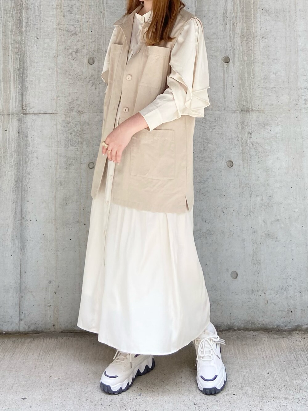 ベージュ系のベスト、ホワイト系のワンピース、ベージュ系のスニーカーを着用したレディースの夏コーディネートの2枚目の写真