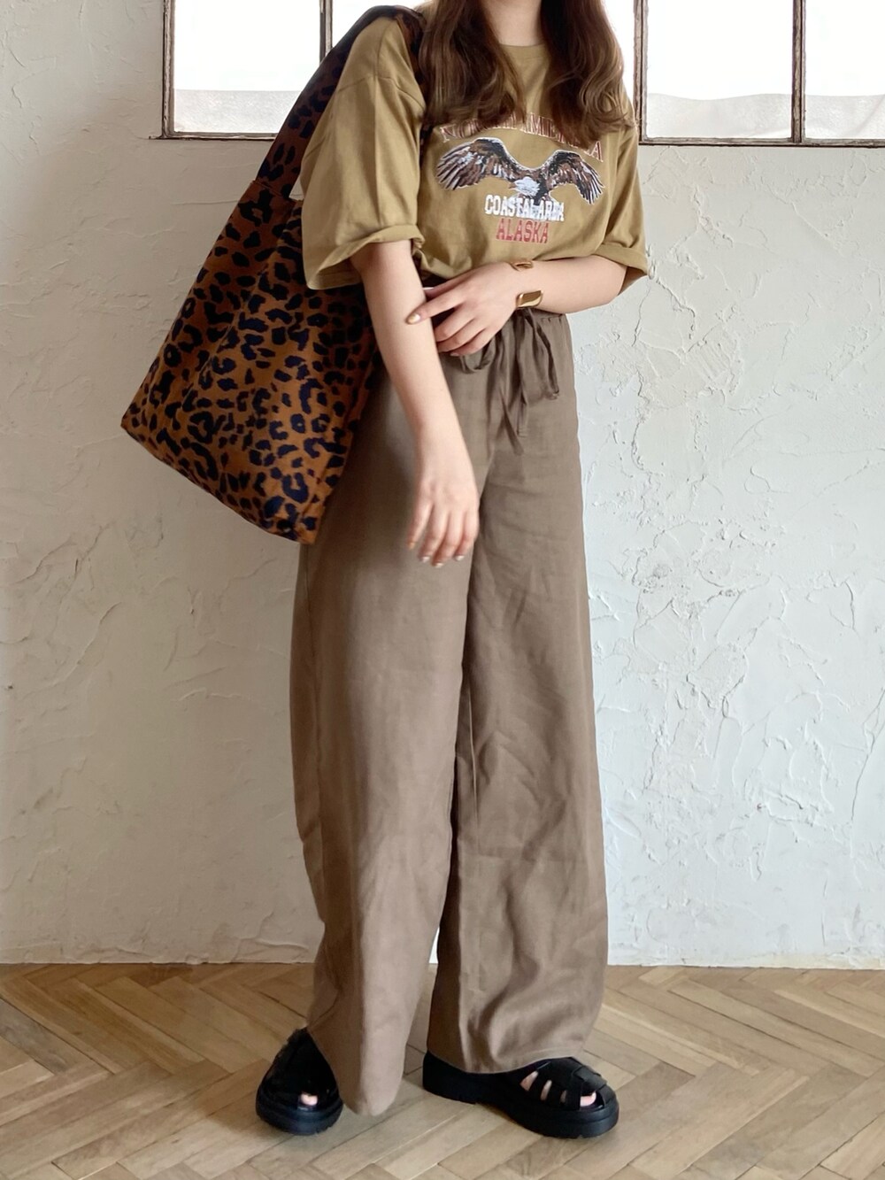 ブラウン系のその他パンツ、ブラック系のサンダル、グリーン系のTシャツ/カットソーを着用したレディースの夏コーディネートの2枚目の写真