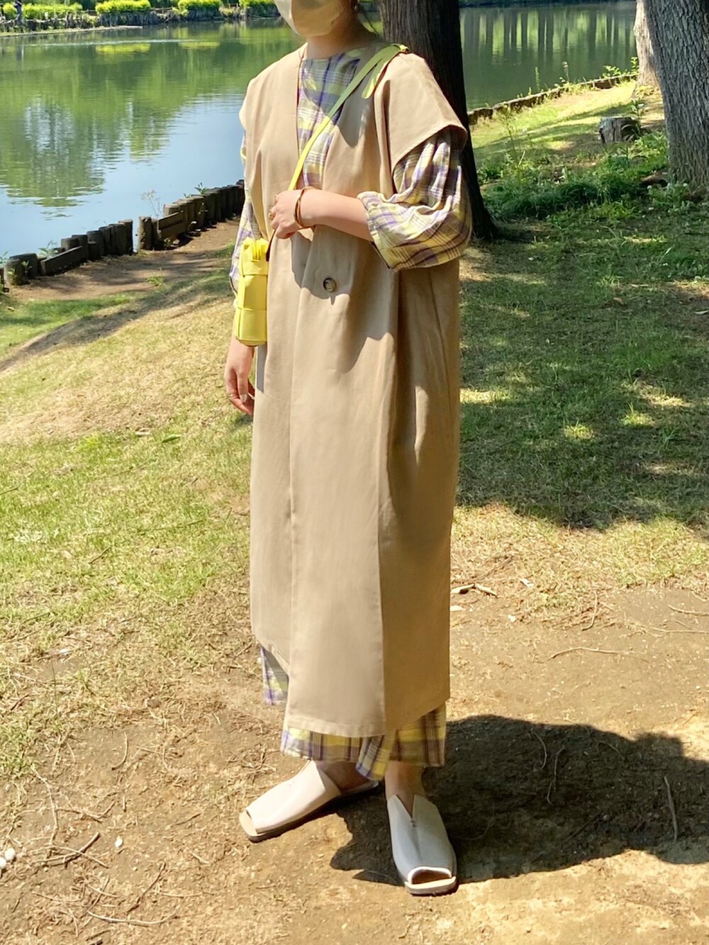 ベージュ系のベスト、ホワイト系のサンダルを着用したレディースの春コーディネートの2枚目の写真