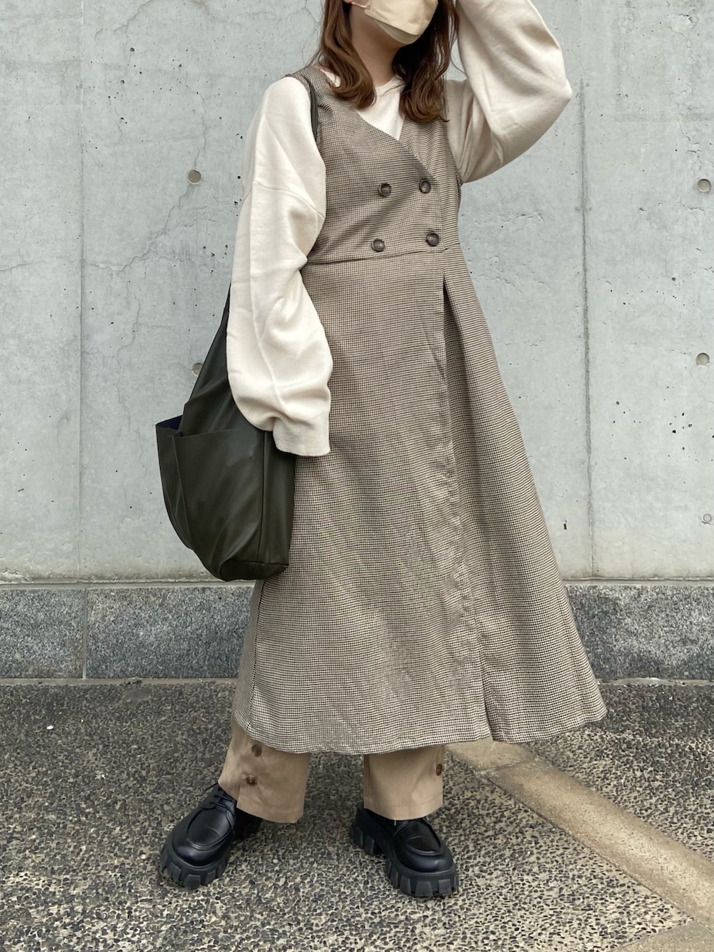 ブラウン系のベスト、ベージュ系のその他パンツ、グリーン系のショルダーバッグを着用したレディースの冬コーディネートの3枚目の写真