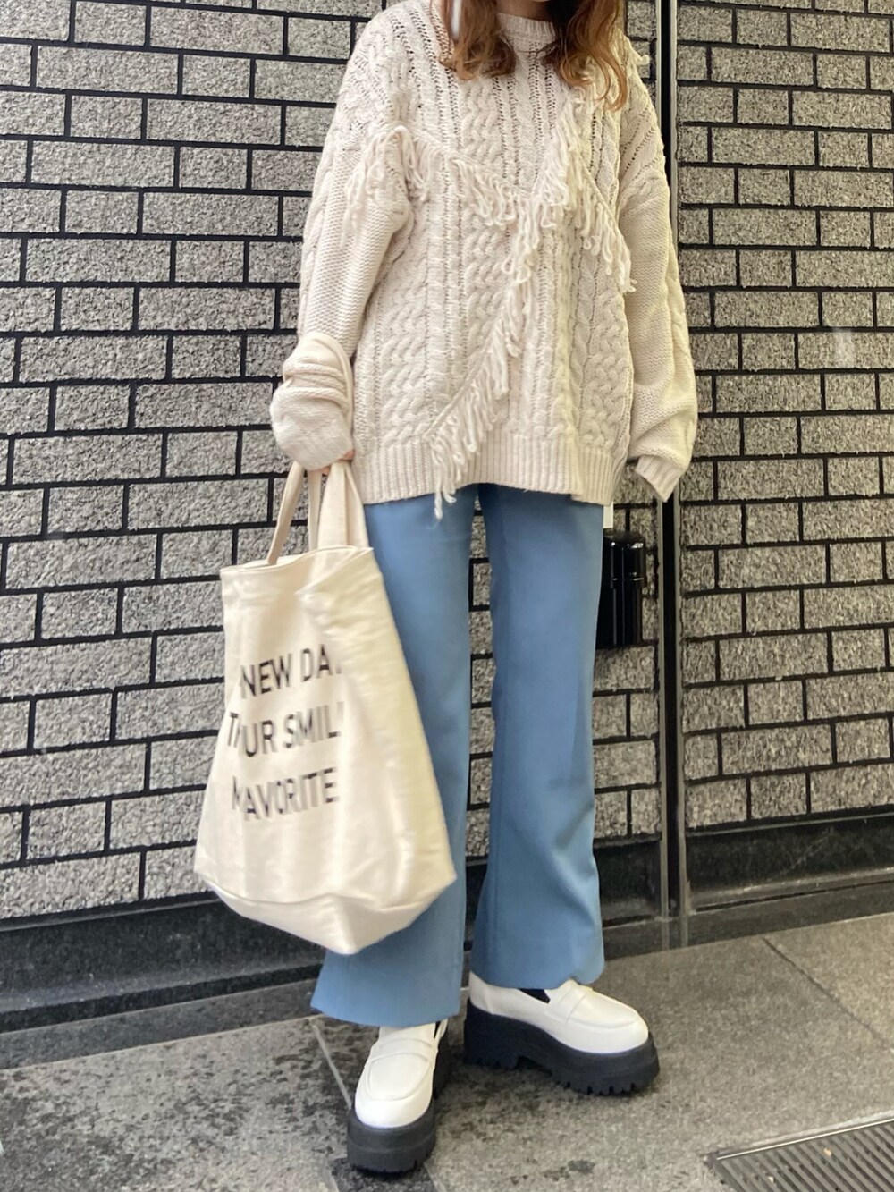 ホワイト系のニット/セーター、ホワイト系のトートバッグ、ホワイト系のローファーを着用したレディースの冬コーディネートの3枚目の写真