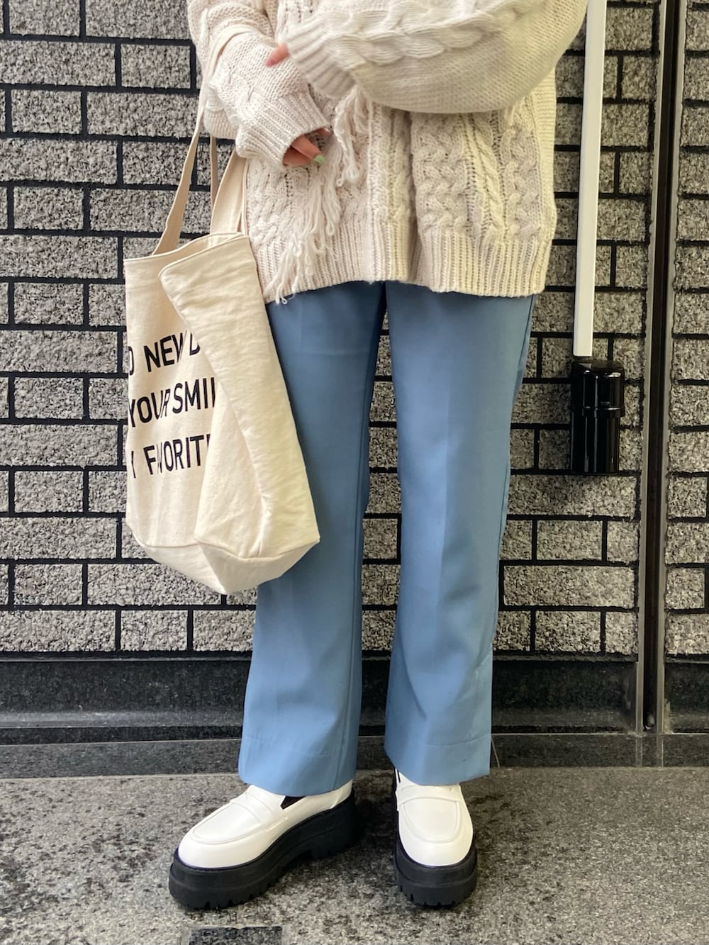 ホワイト系のニット/セーター、ホワイト系のトートバッグ、ホワイト系のローファーを着用したレディースの冬コーディネートの5枚目の写真