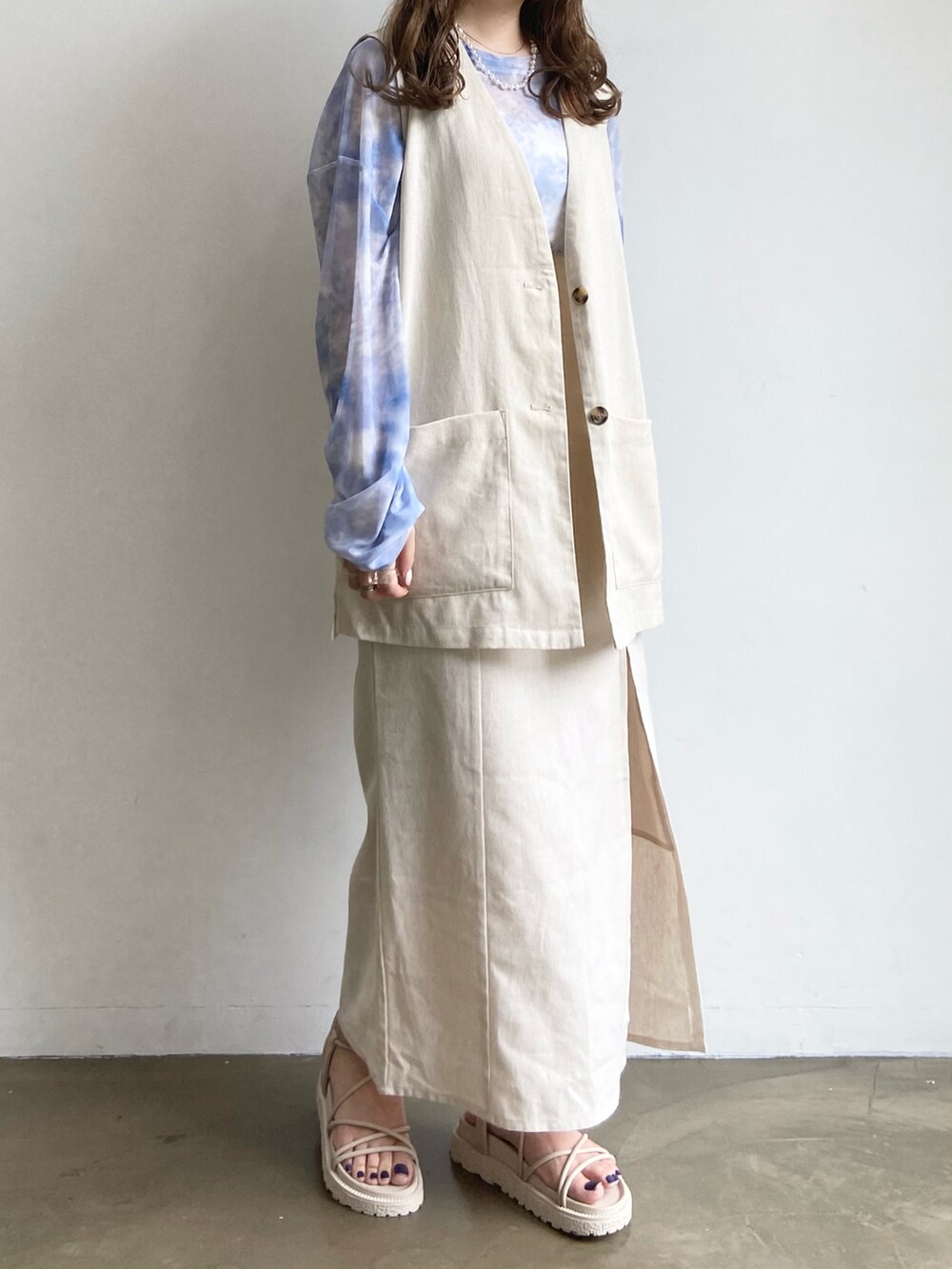 ベージュ系のベスト、ブルー系のTシャツ/カットソー、ベージュ系のサンダルを着用したレディースの夏コーディネートの2枚目の写真